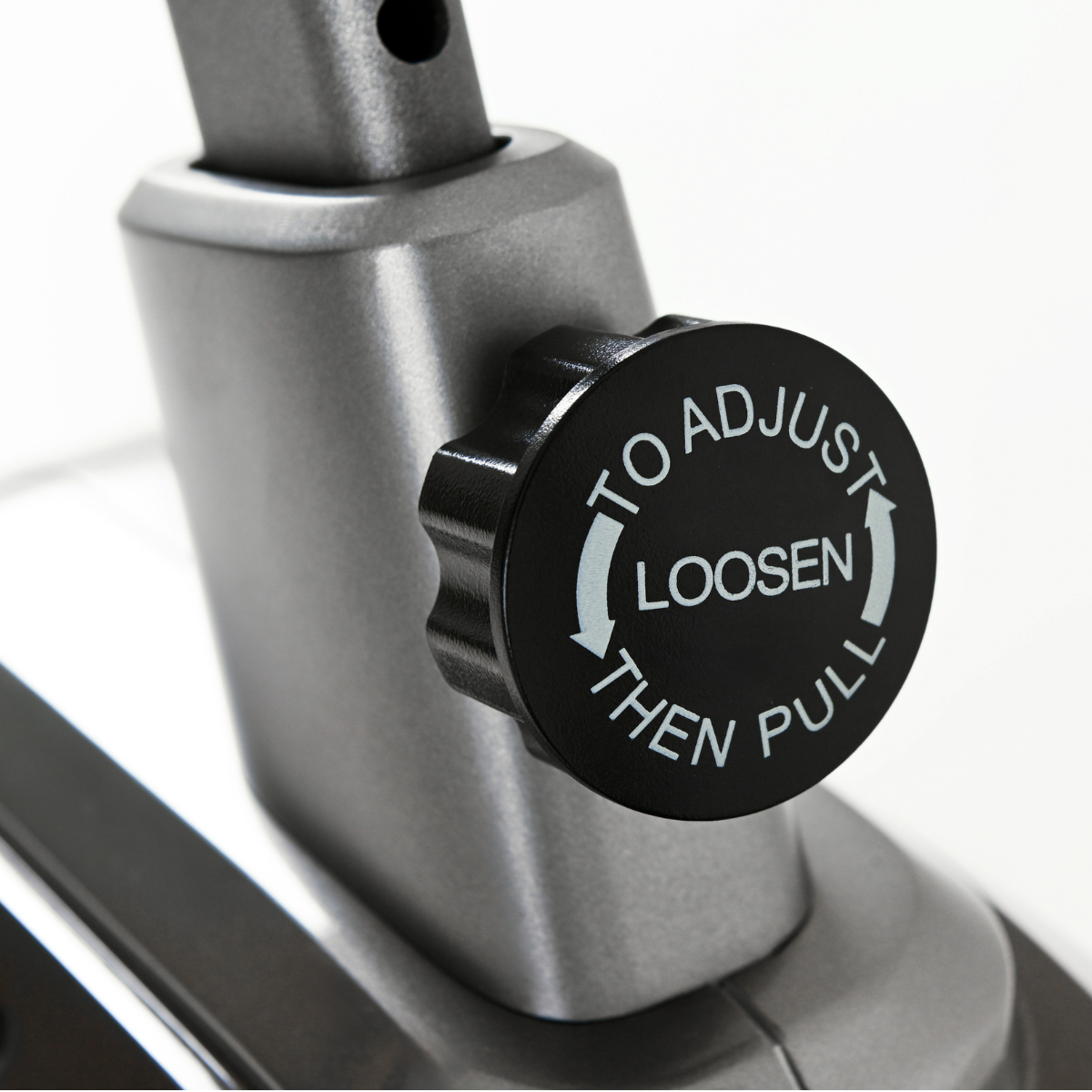 Nahaufnahme eines schwarzen Knopfes an einer grauen Maschine. Text: Einstellen, Lösen, Dann Ziehen.