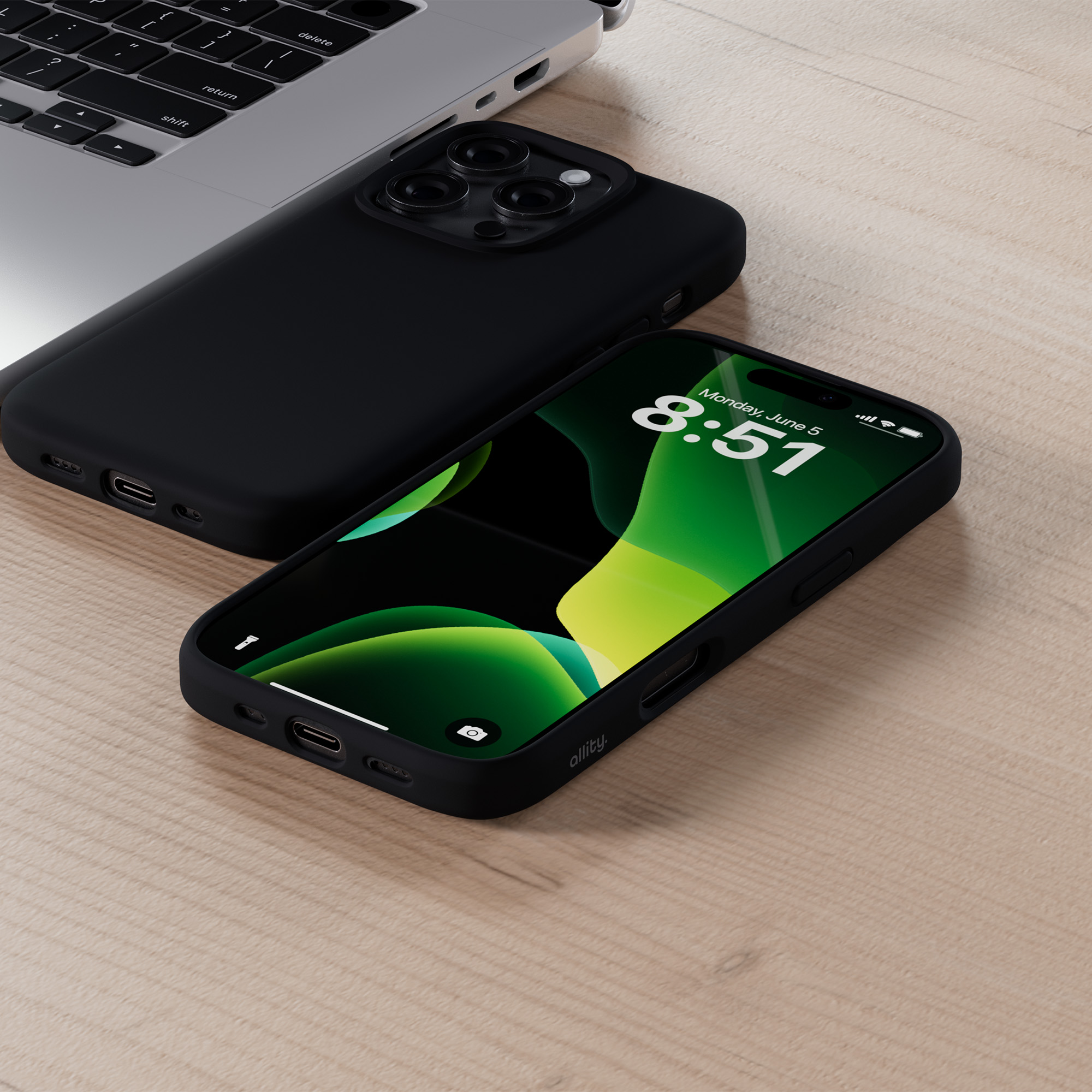 Czarny telefon na drewnianym stole obok czarnej obudowy i laptopa.