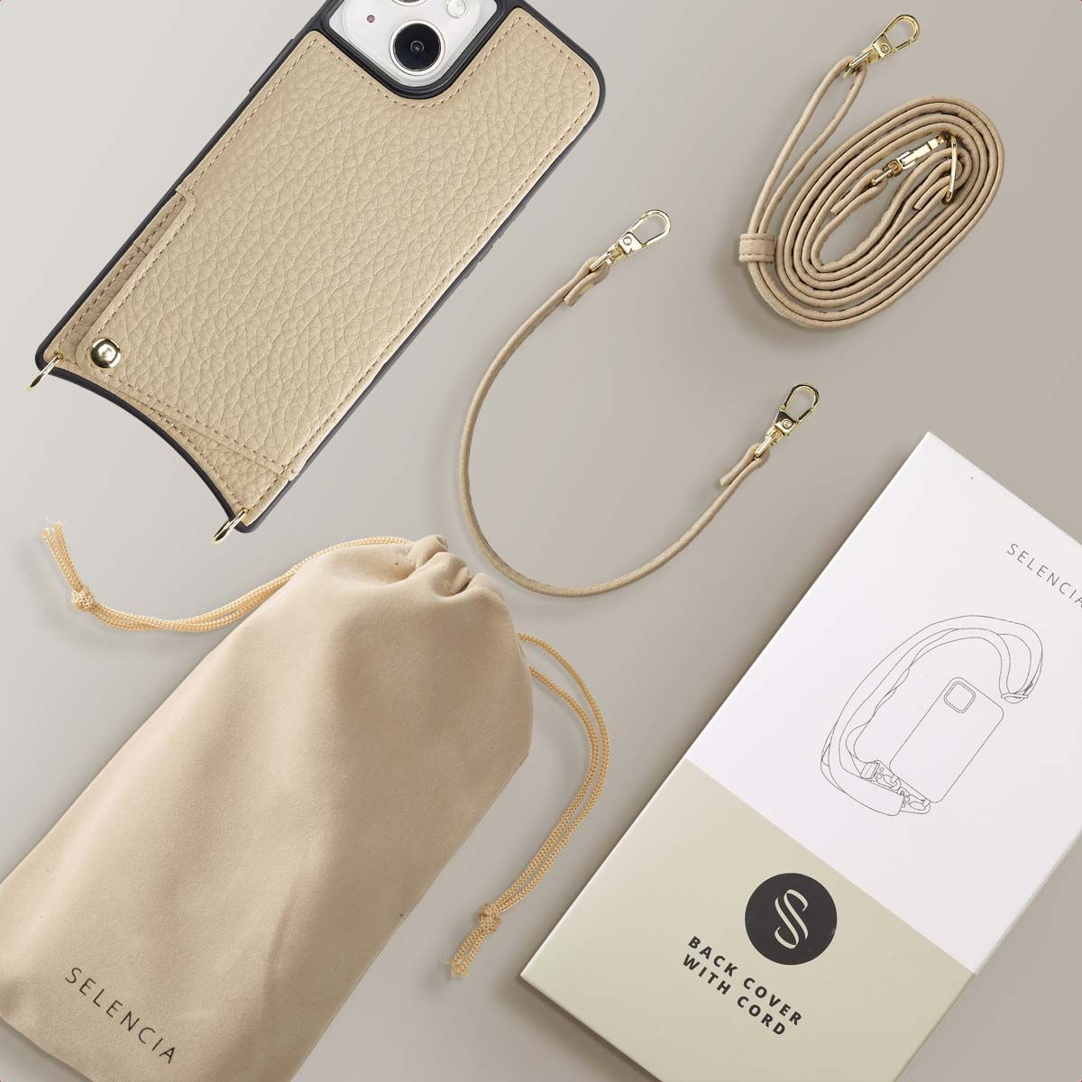 Coque de téléphone beige avec cordon, sac et boîte. Surface blanche.