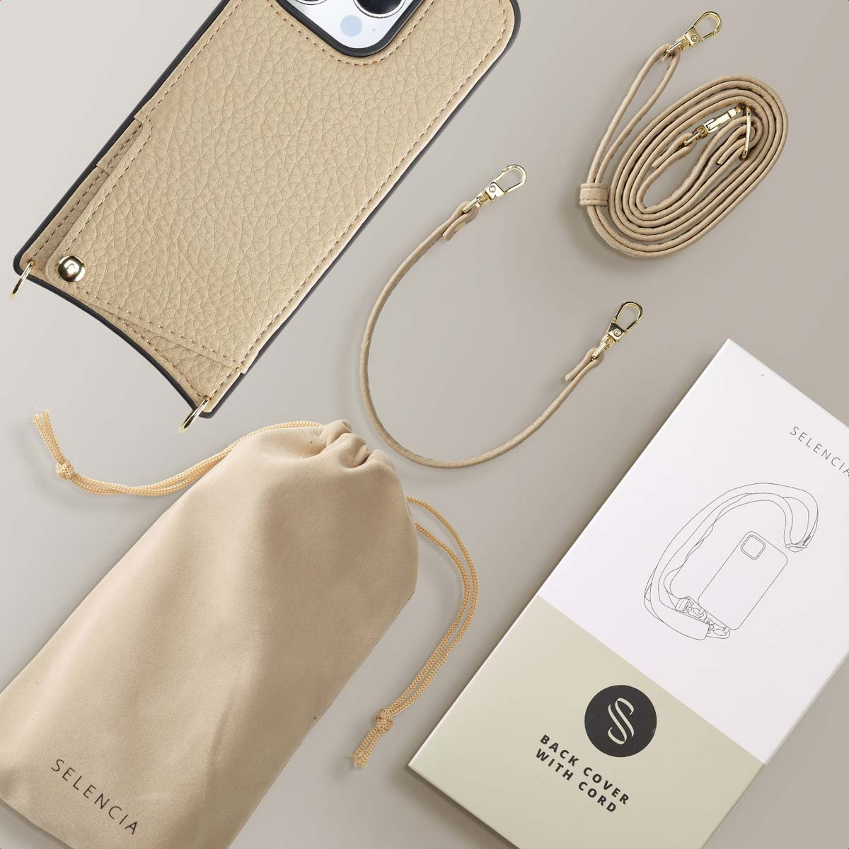 Een beige telefoonhoesje met een koord, een apart koord, een zakje en een doos met tekst.