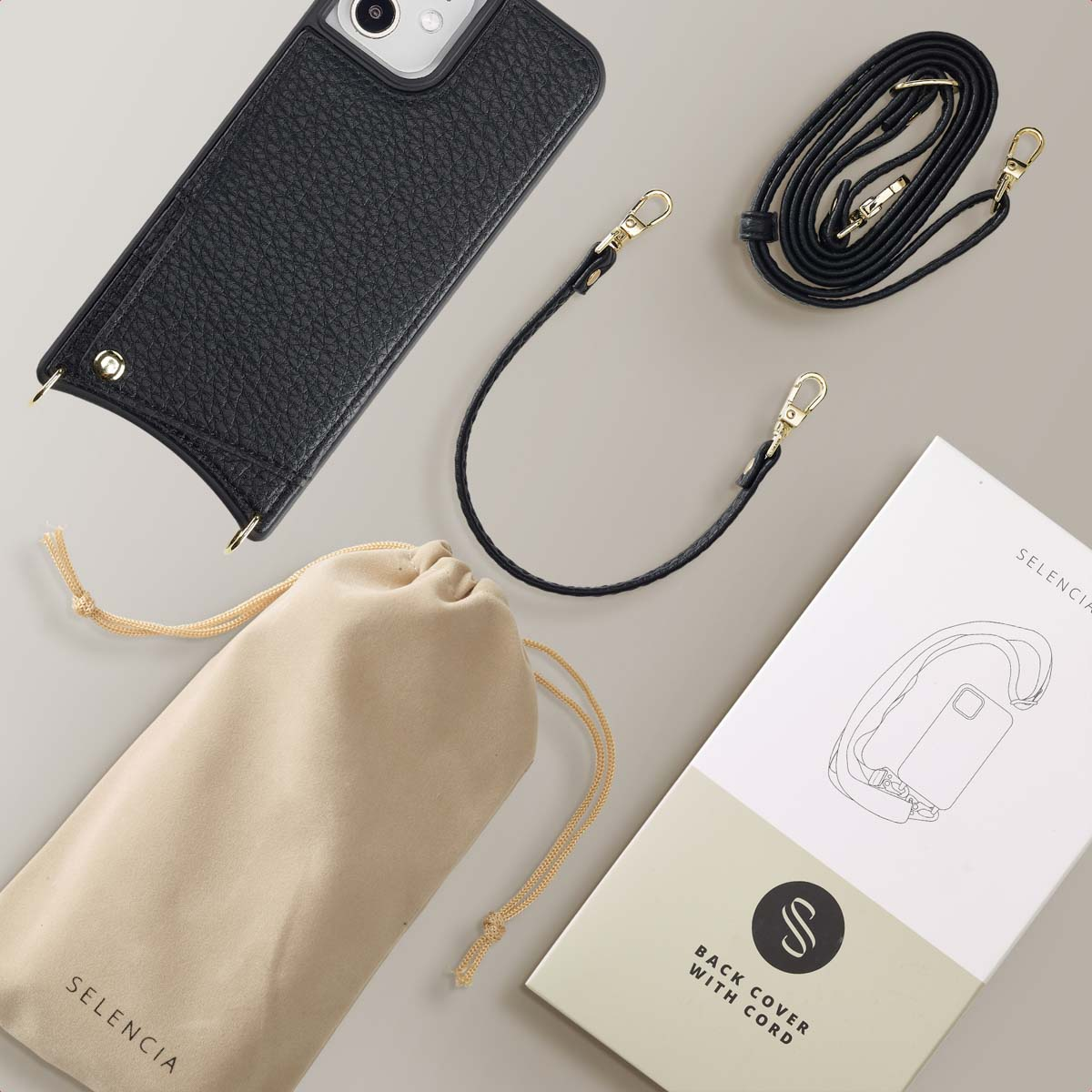 Een telefoonhoesje met een riem, een tas en een doos met Selencia-merk.