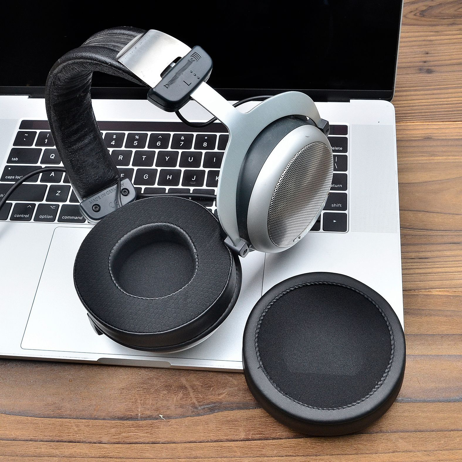 Słuchawki na klawiaturze laptopa, z dodatkową wkładką douszną obok słuchawek.