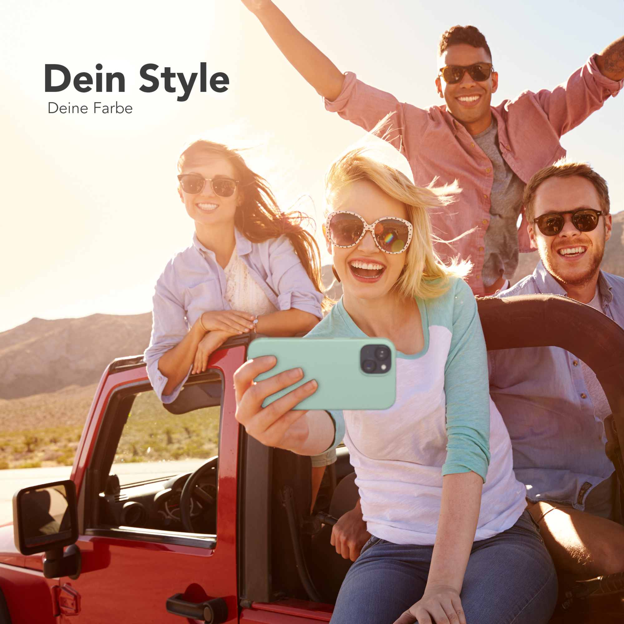 Eine Gruppe von vier Personen lächelt und macht ein Selfie mit einem Telefon in einem roten Jeep.