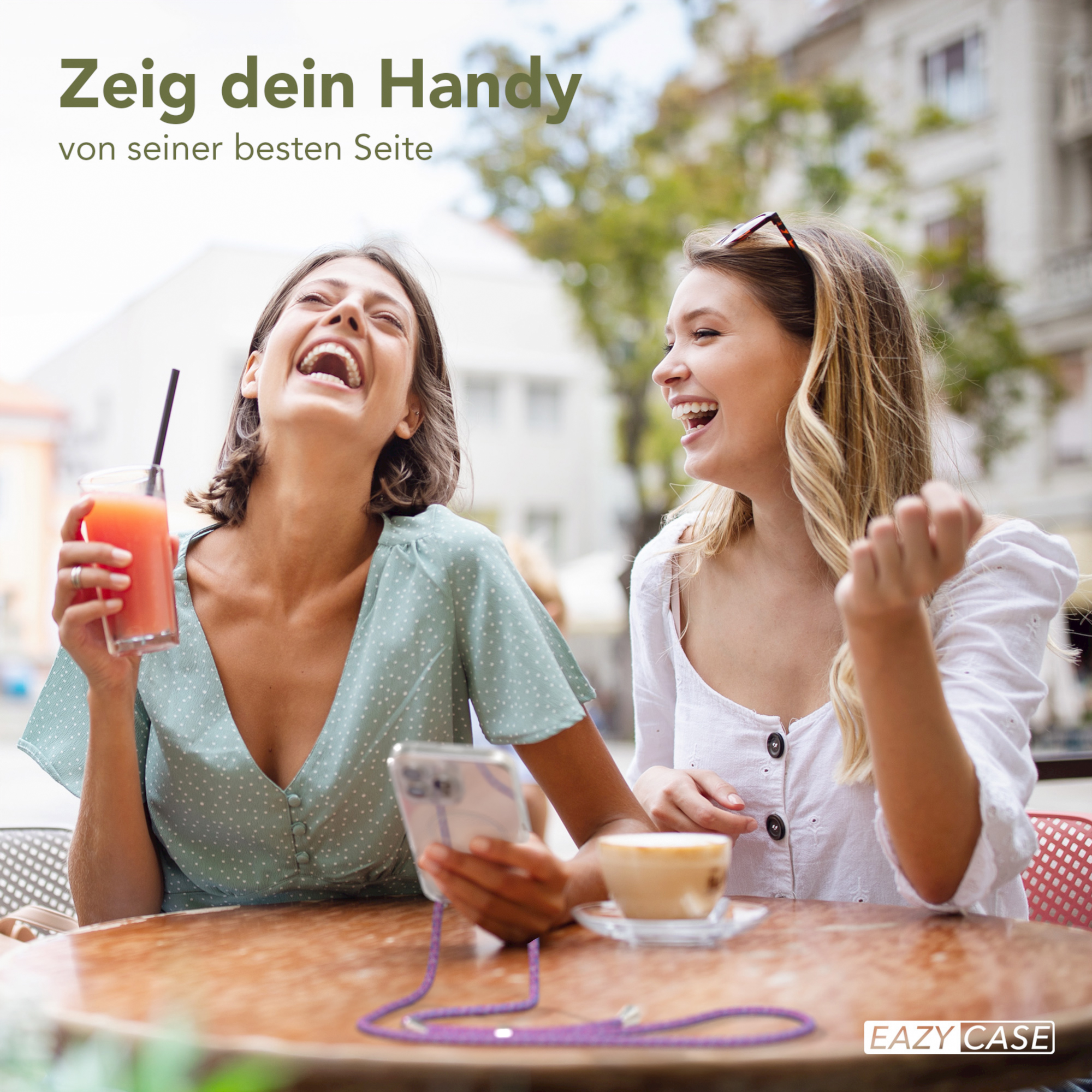 Zwei lachende Frauen, die Getränke halten, mit einer Handyhülle und einem Gurt, im Freien.