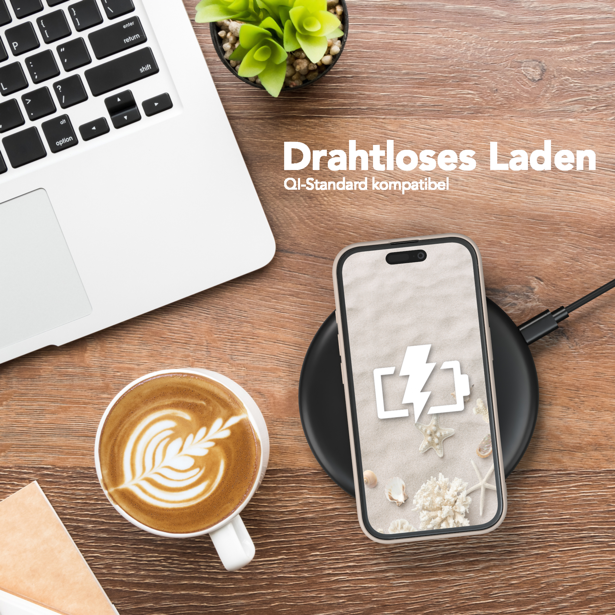 Ein Telefon, das drahtlos auf einem Ladepad geladen wird, neben einem Laptop und einer Tasse Kaffee.