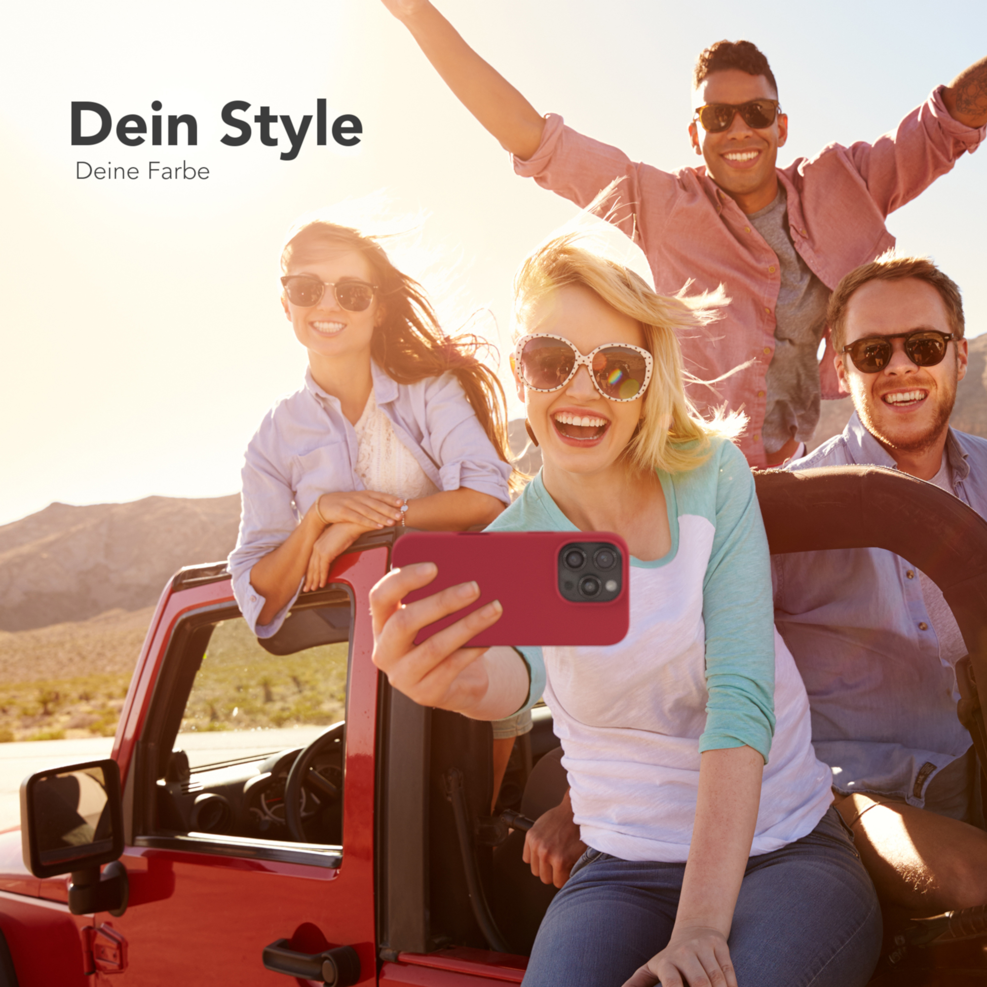 Vier lächelnde Personen in einem roten Jeep. Einer macht ein Selfie mit einer roten Handyhülle.