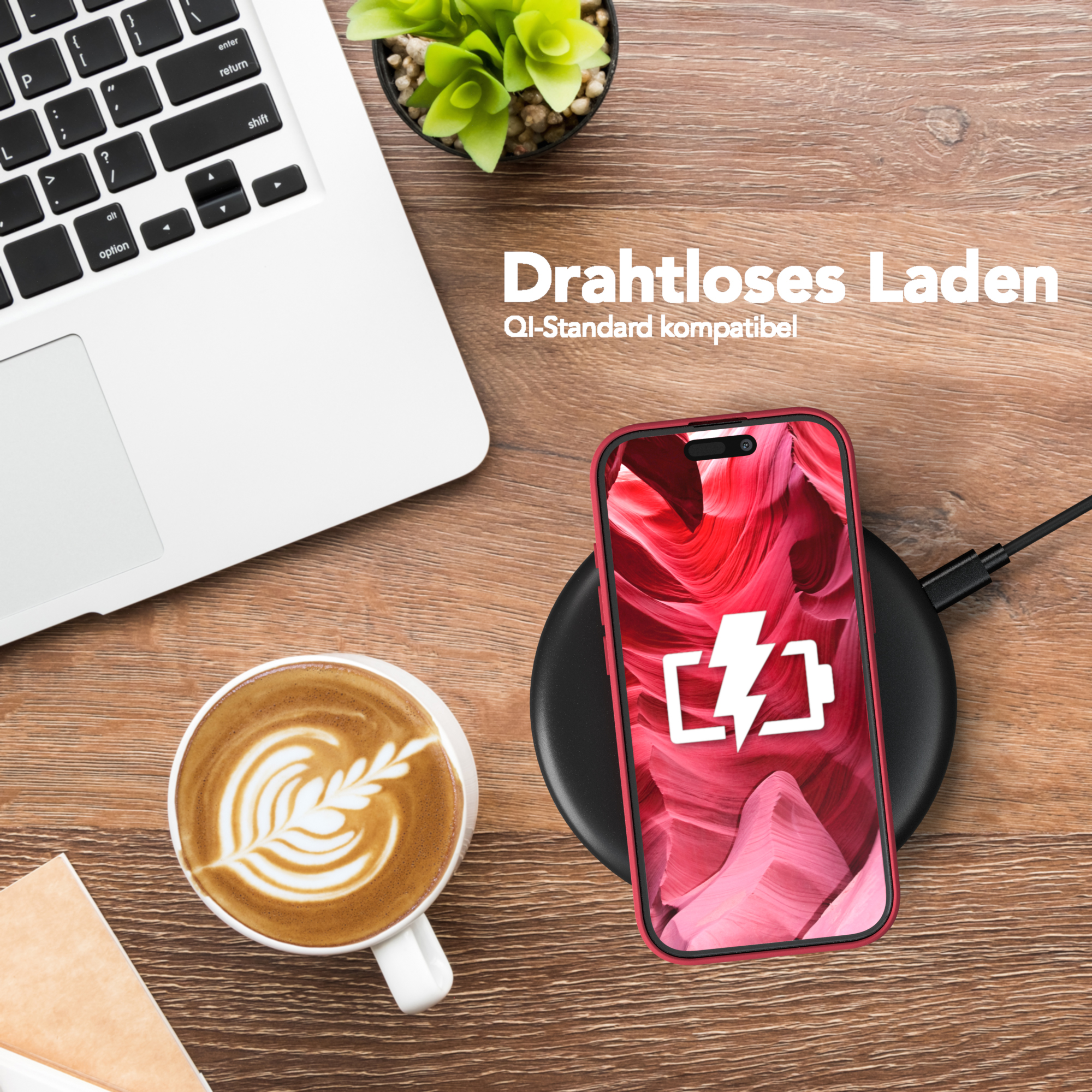 Ein Telefon mit roter Hülle wird drahtlos auf einem schwarzen Pad geladen. Eine Tasse Kaffee und ein Laptop stehen ebenfalls auf dem Tisch.