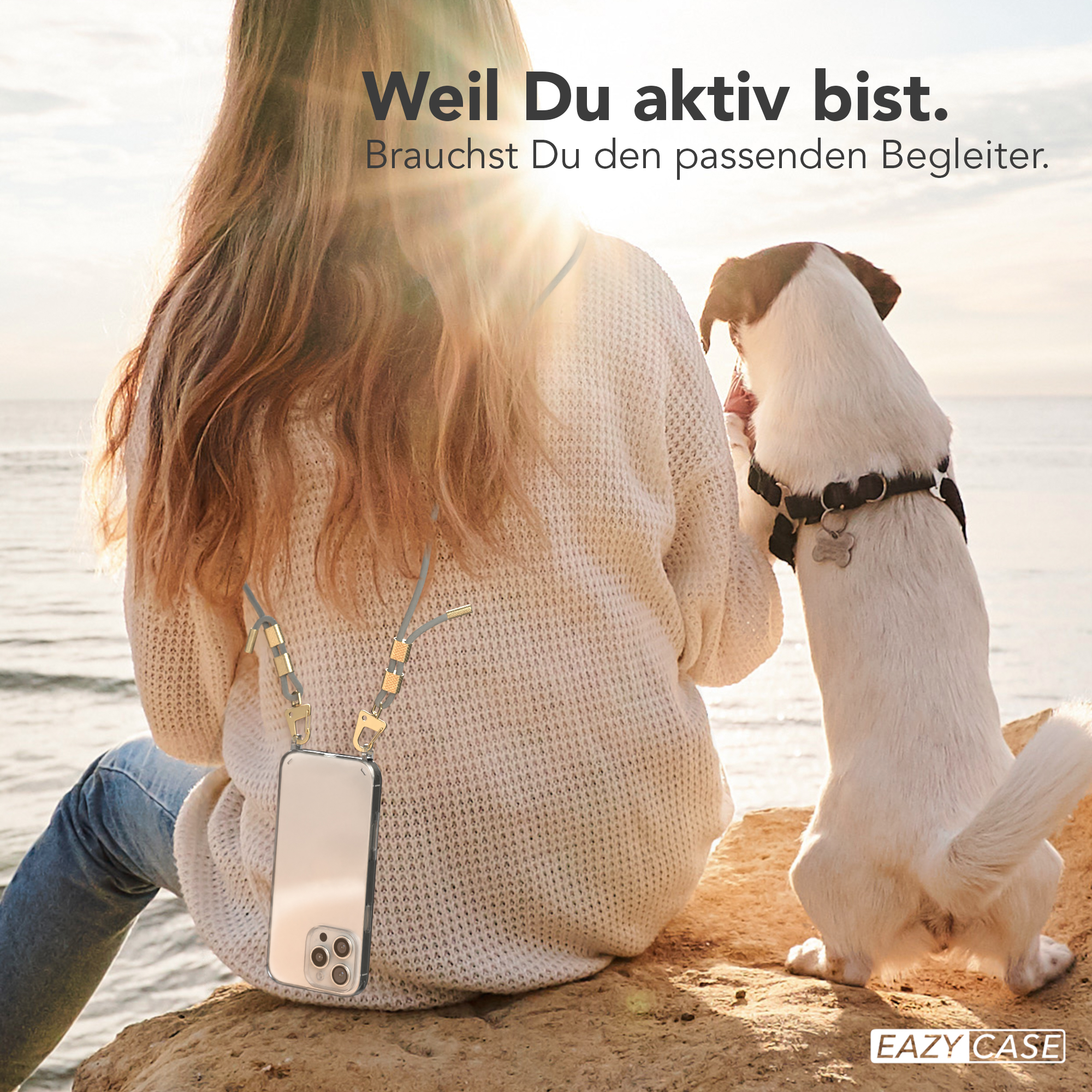 Eine Frau und ihr Hund am Strand, wobei der Hund auf den Handyhüllenriemen schaut.