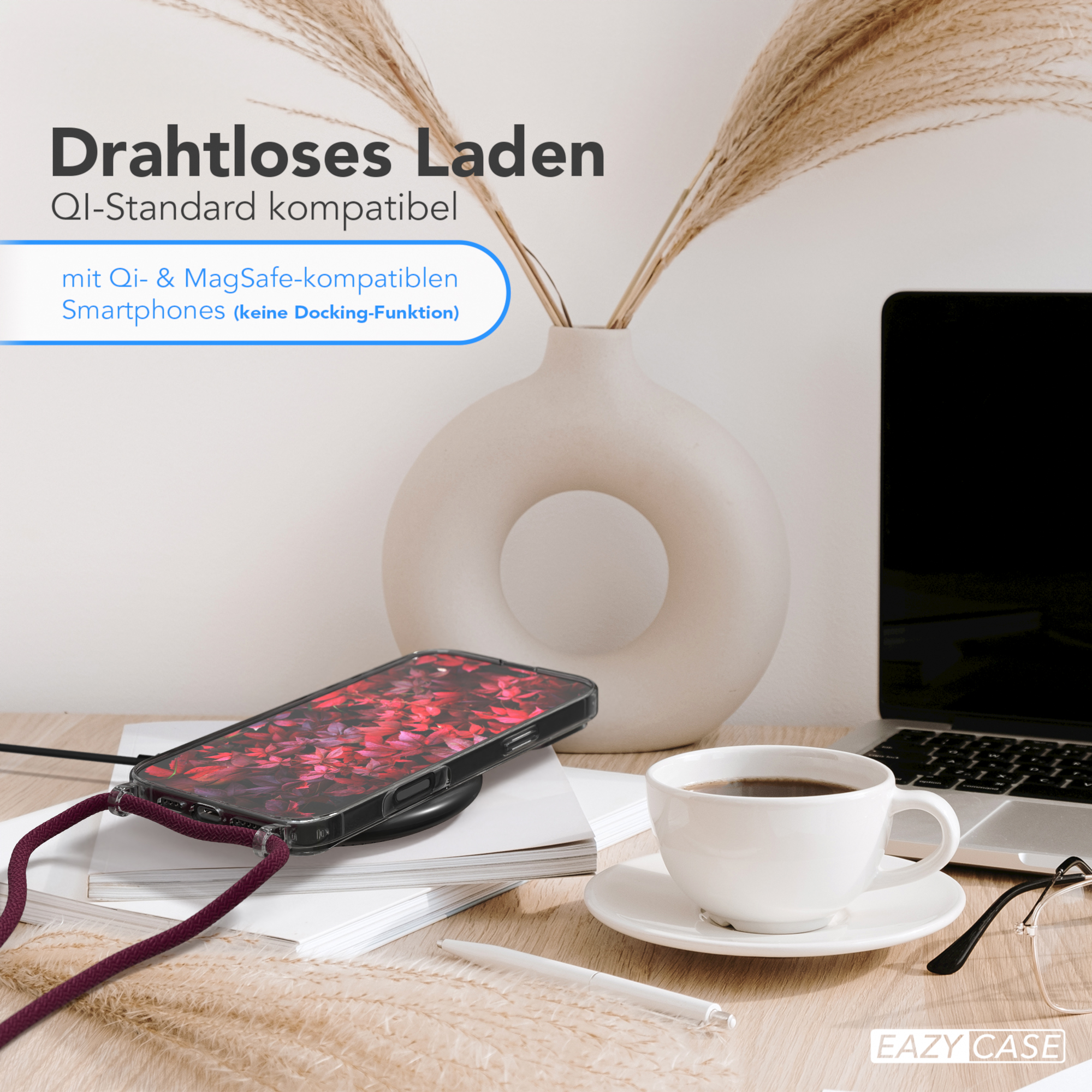 Ein Telefon, das drahtlos auf einem Schreibtisch geladen wird, mit einer Vase mit Blumen und einer Tasse Kaffee.