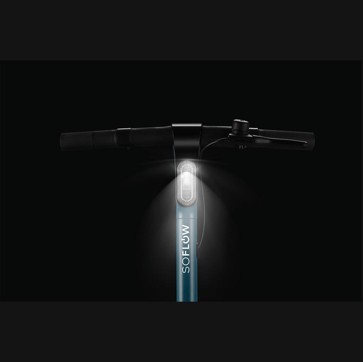 Manubrio di e-scooter con faro luminoso, illuminato su sfondo nero.