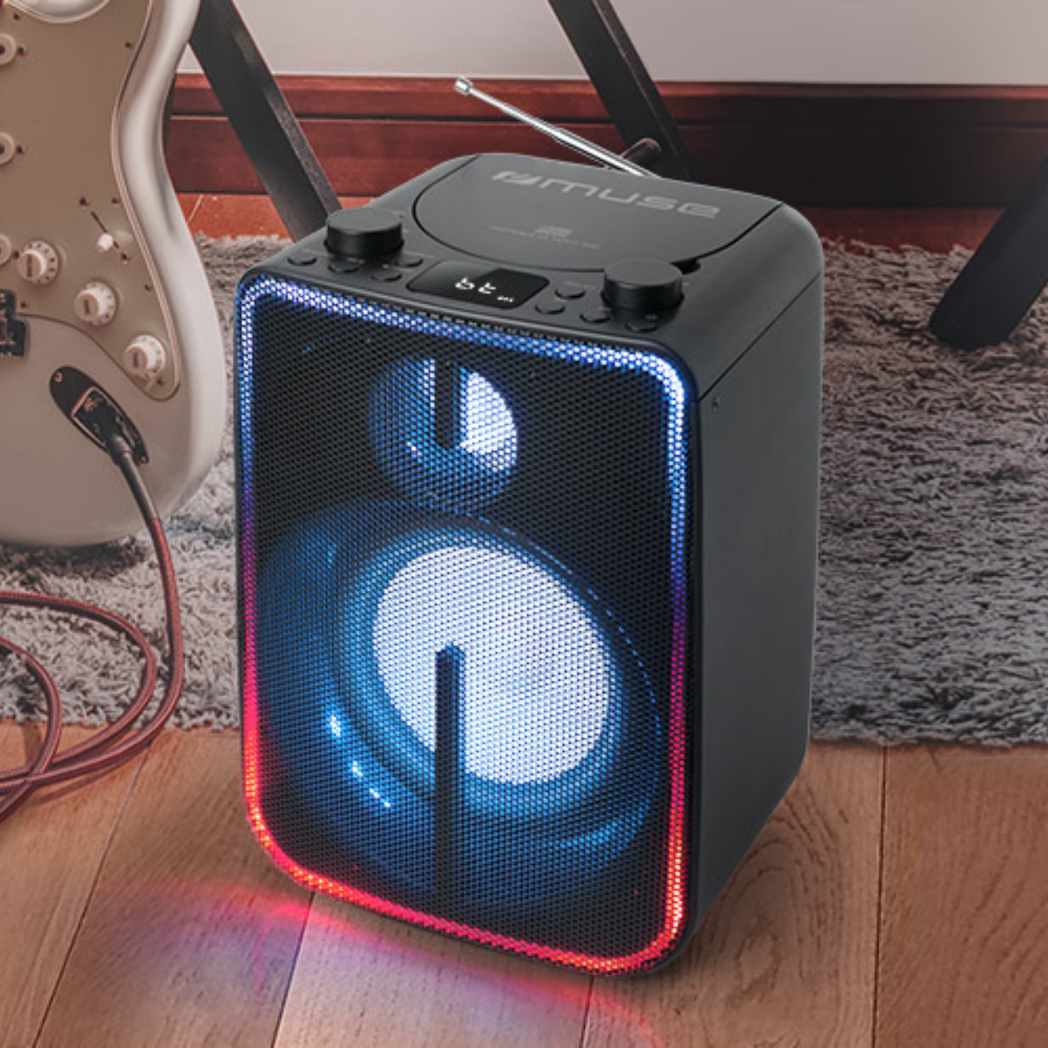 Altoparlante nero con luci blu e rosse. È su un pavimento in legno e ha un logo Muse.