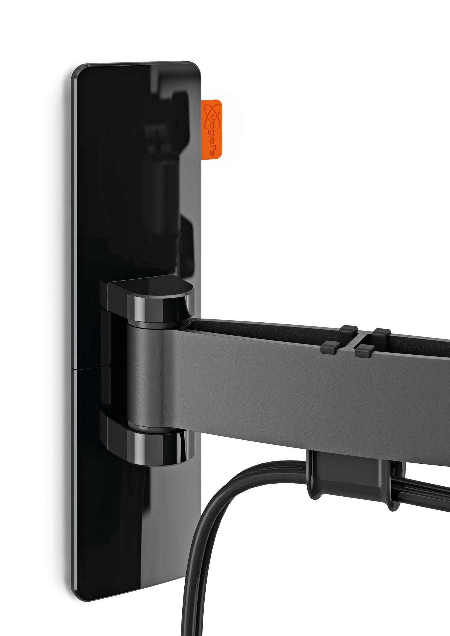 Eine schwarze TV-Wandhalterung an einer weißen Wand mit einem orangefarbenen Etikett.