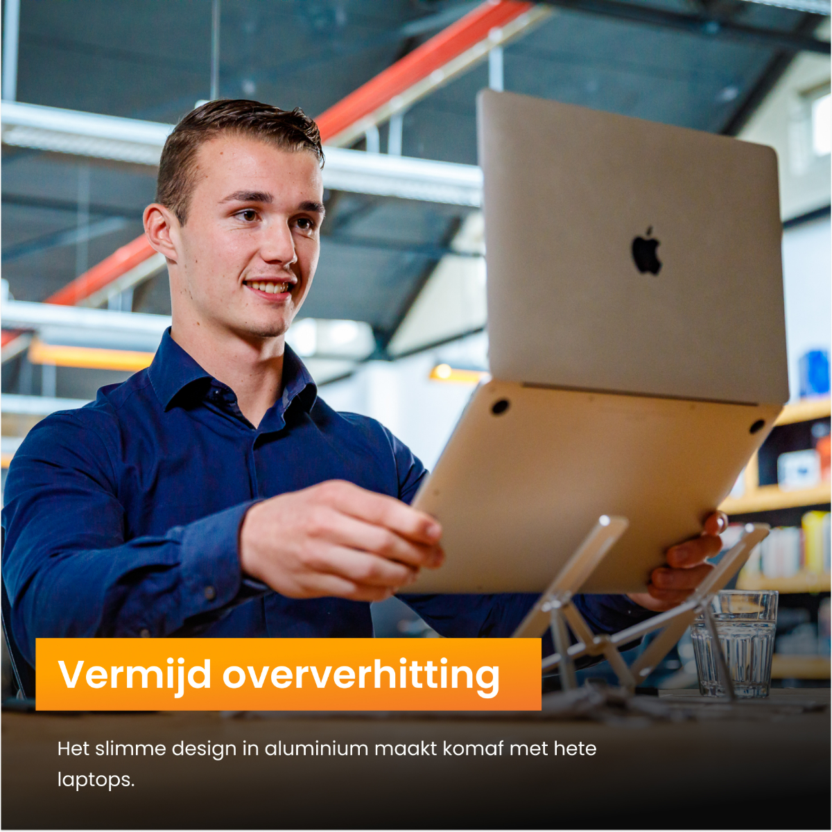 Een man met een laptop. Laptop opengeklapt op een standaard. De man lacht.