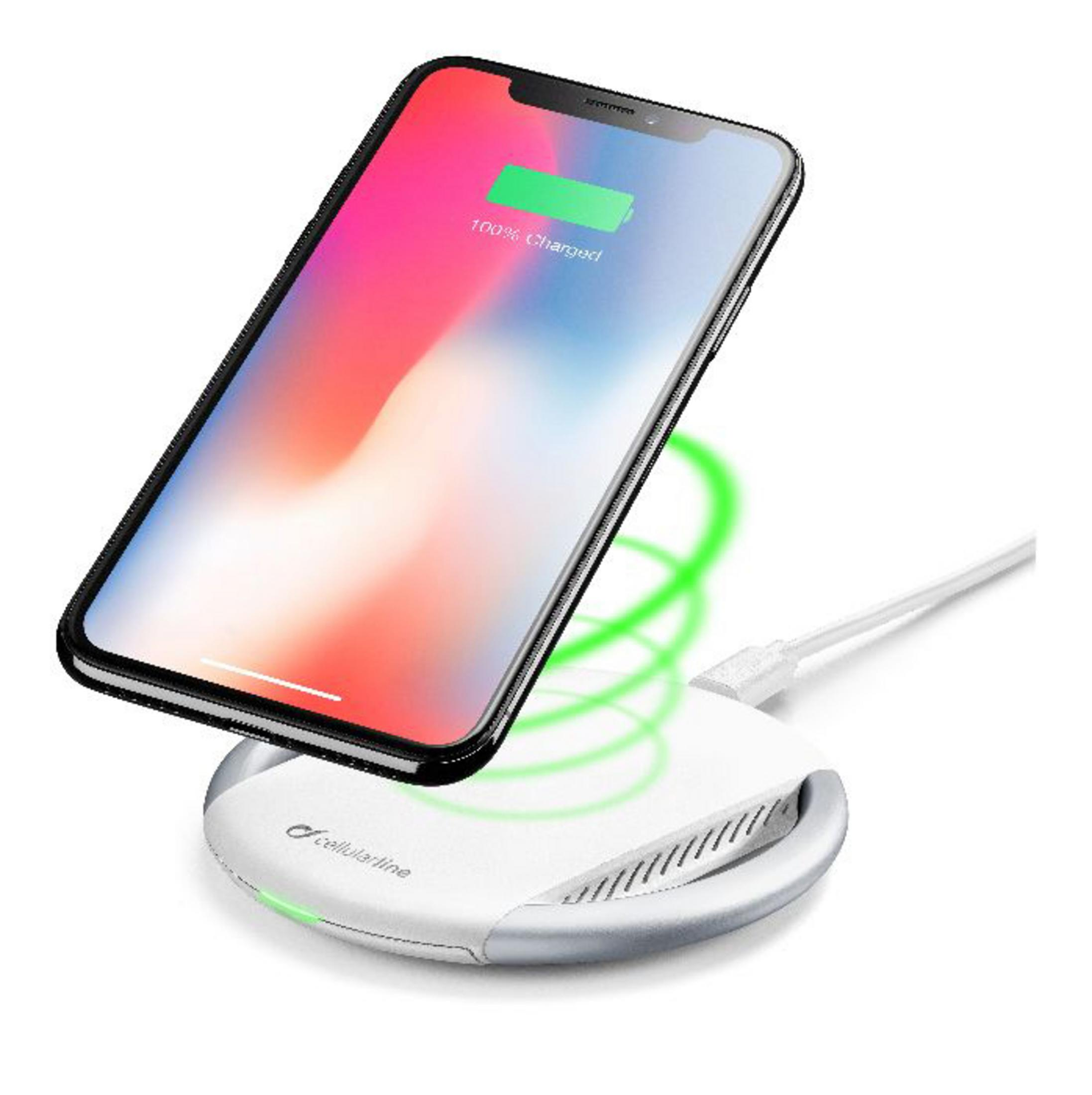 Un teléfono cargando de forma inalámbrica. Muestra 100% cargado, sobre una base blanca con luz verde.
