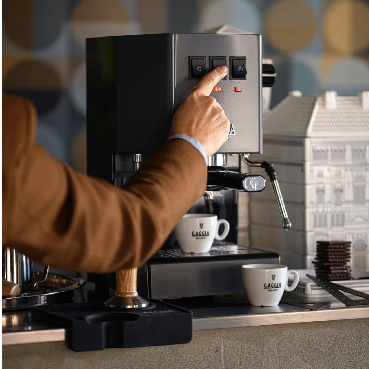 Osoba korzysta z ekspresu do kawy. Osoba naciska przycisk na czarno-srebrnym ekspresie do espresso.