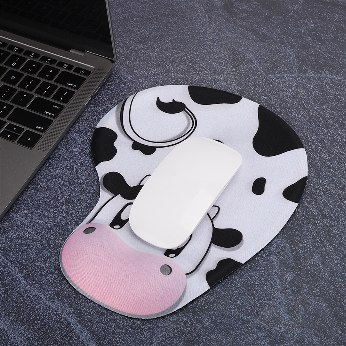 Mauspad im Kuh-Design mit weißer Maus. Laptop teilweise links sichtbar.