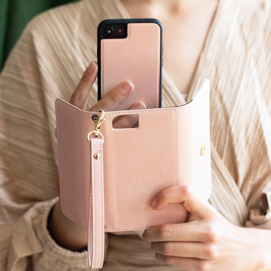 Personne tenant un téléphone dans un étui rose avec une dragonne.