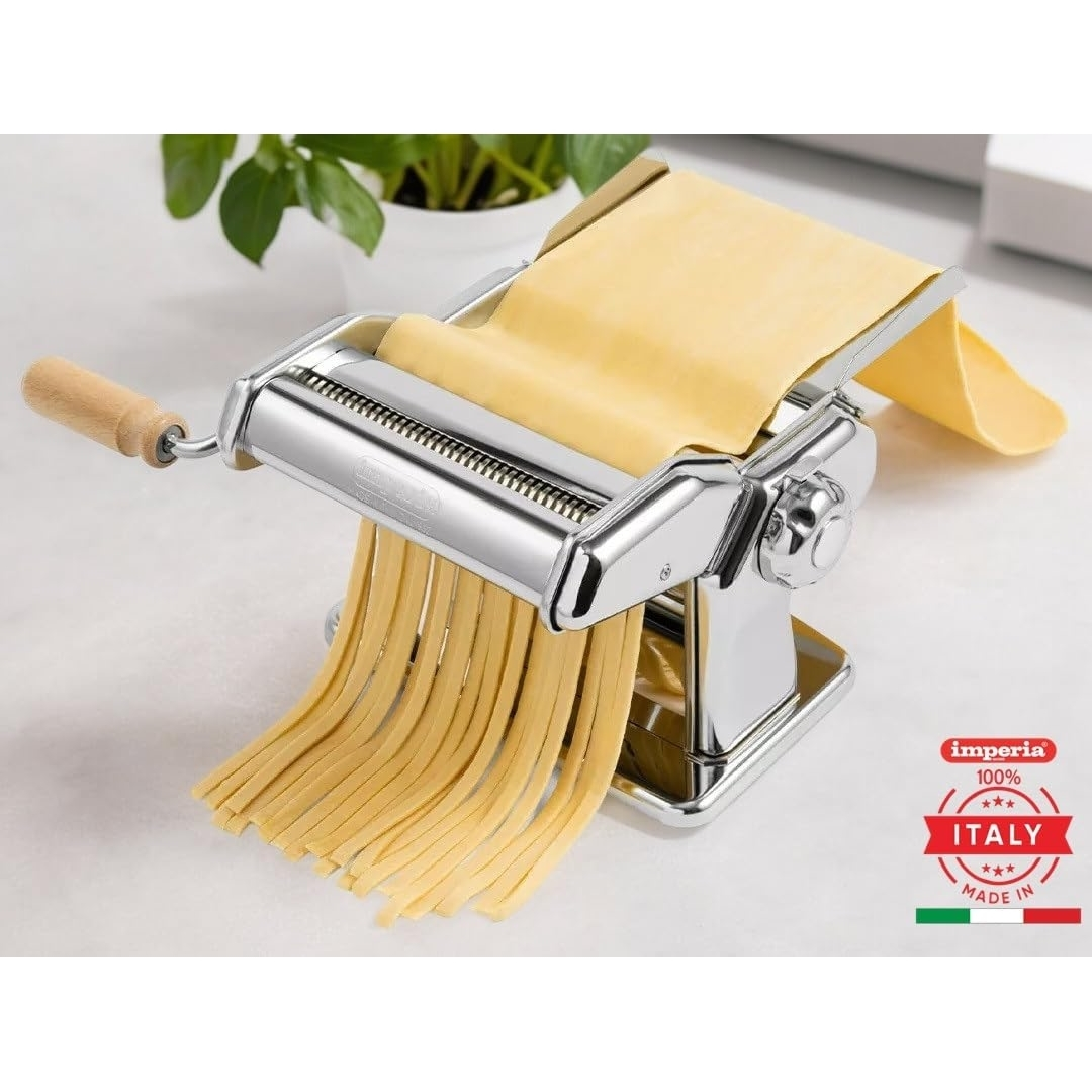 Una macchina per la pasta argentata con manico in legno sta facendo la pasta. La pasta fresca pende.