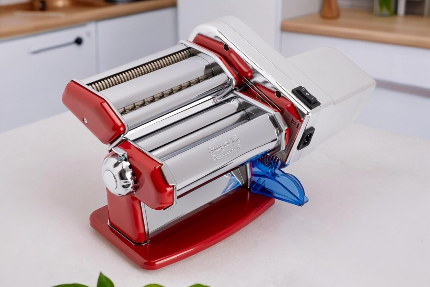 Macchina per la pasta rossa con rulli argentati e parte superiore argentata. Lo sfondo è bianco.