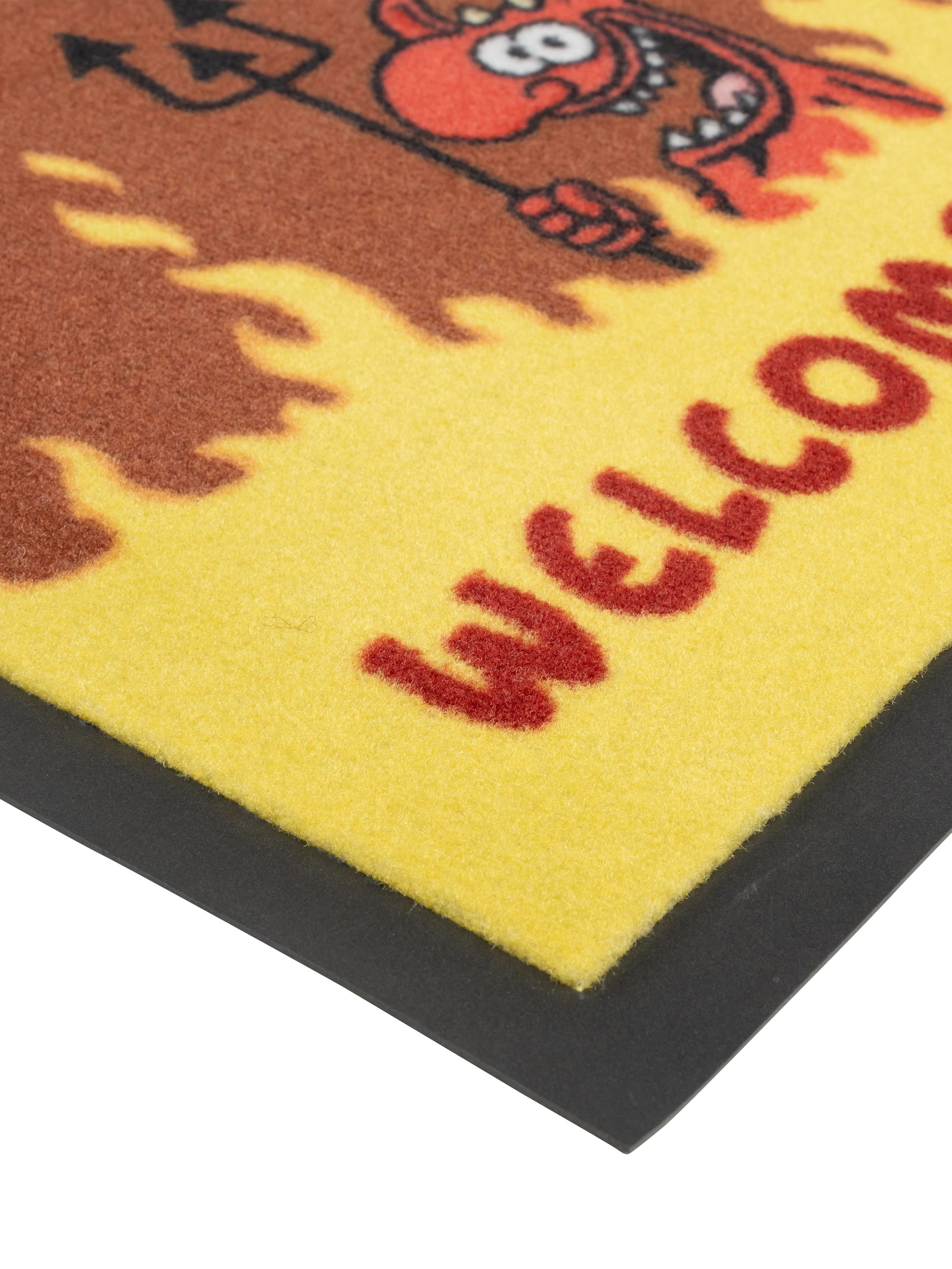 Willkommen-Matte mit Teufelsfigur. Gelber Hintergrund mit rotem Willkommenstext.