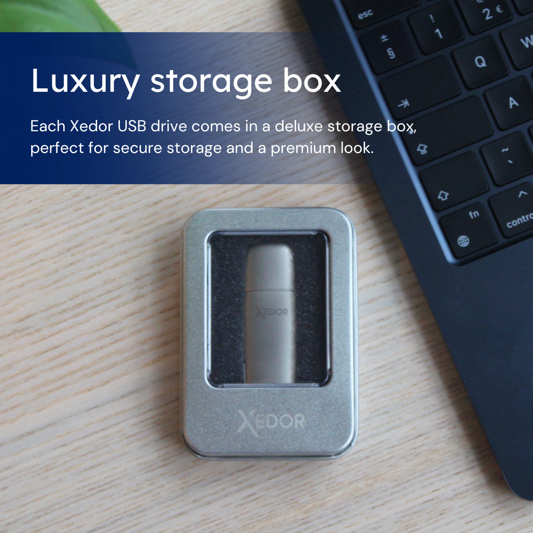 Een zilveren USB-stick in een kleine, zilveren hoes op een houten tafel met een laptop.