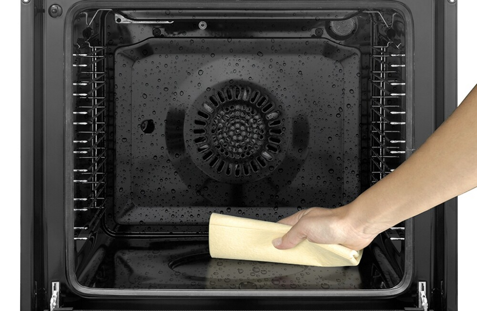 Un interno forno aperto. Una mano pulisce l'interno con un panno giallo.
