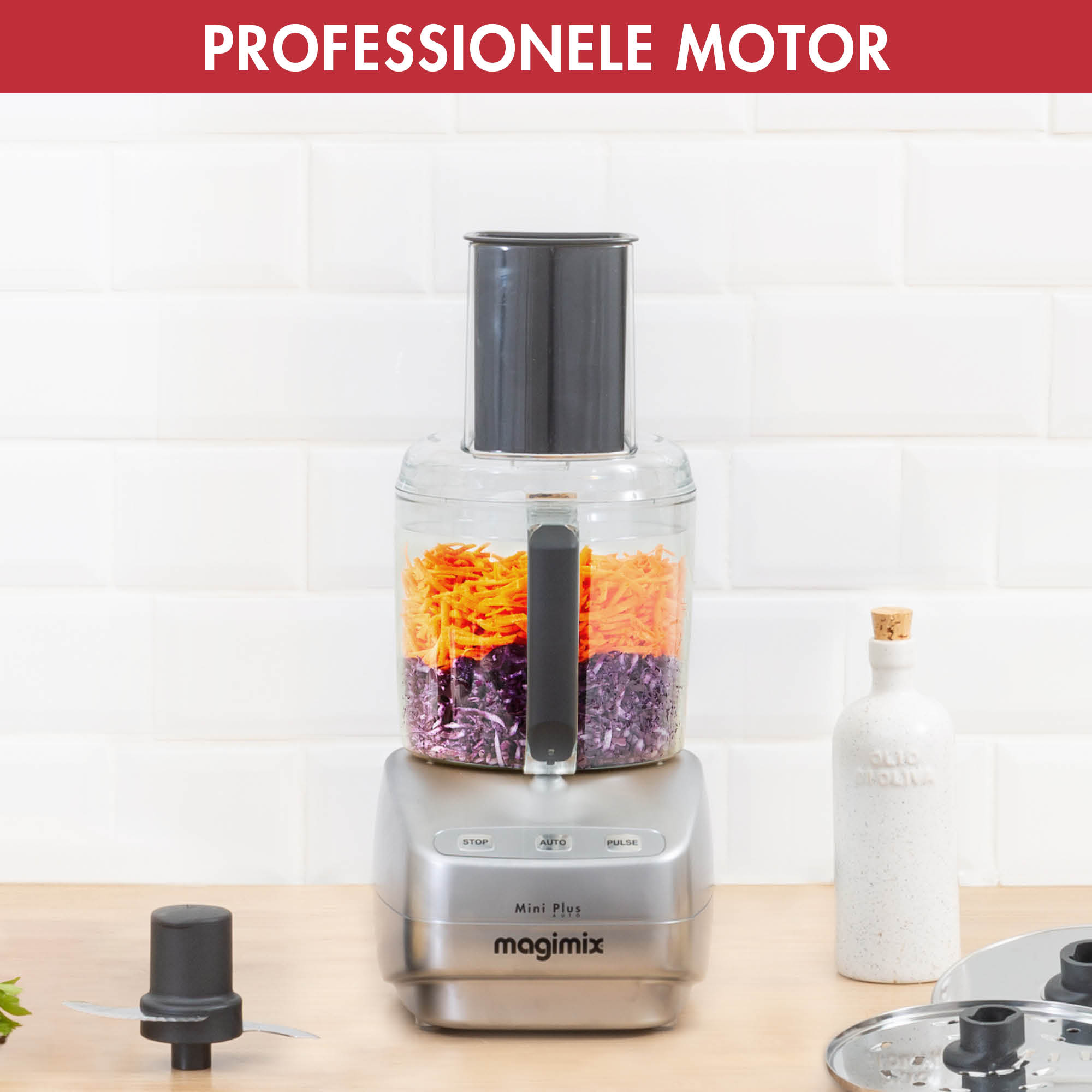 Keukenmachine met wortels en paarse kool erin, plus een fles en messen.