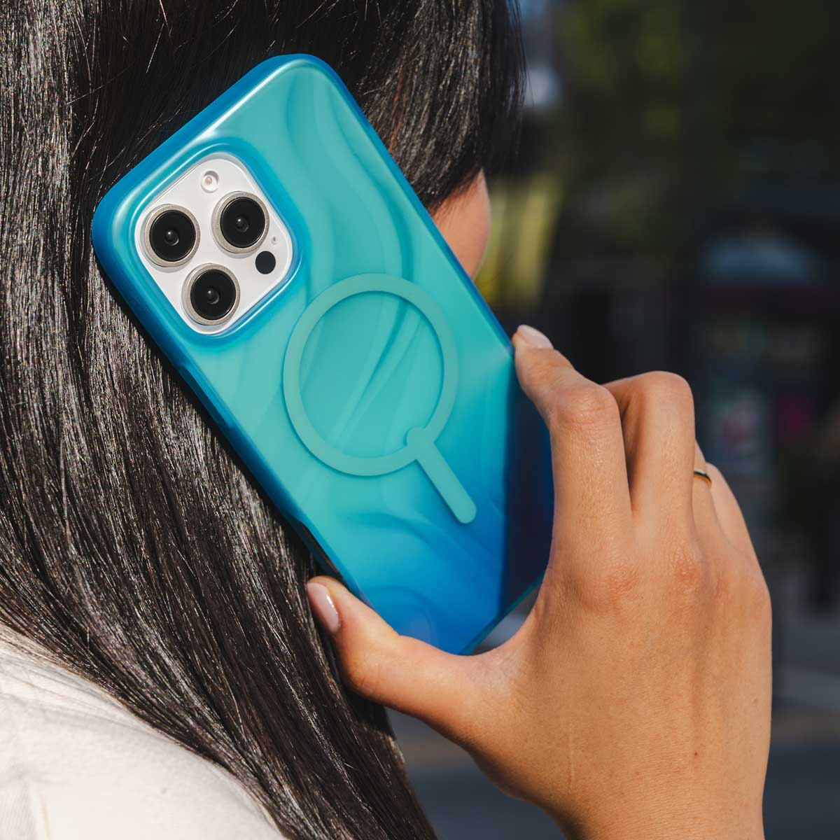 Vrouw houdt blauwe telefoonhoes vast met drie camera's en een ring.