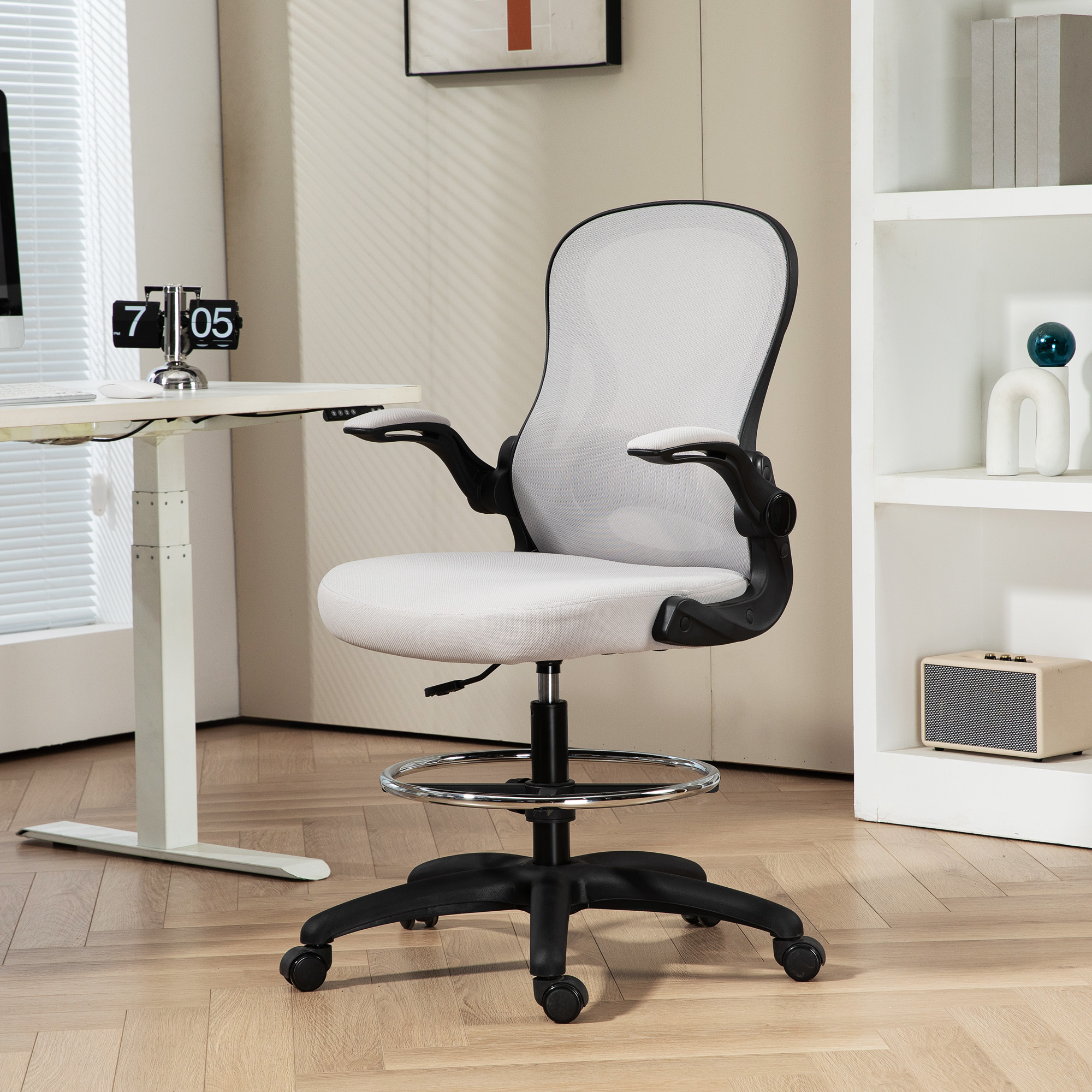 Silla de oficina blanca y negra con respaldo de malla, reposabrazos y anillo para pies. Escritorio atrás.
