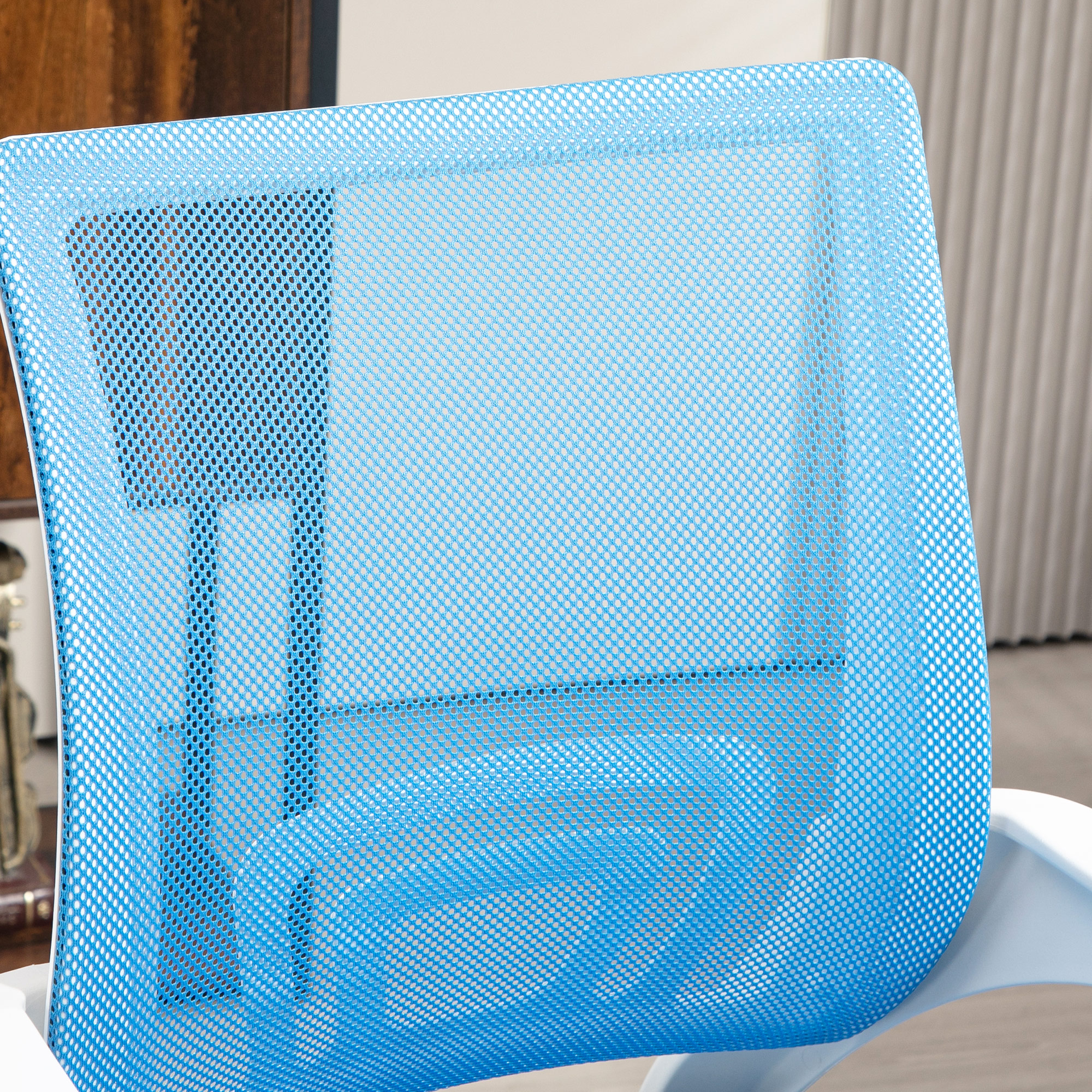 El respaldo de malla azul de una silla de oficina. La silla es blanca y el fondo está borroso.