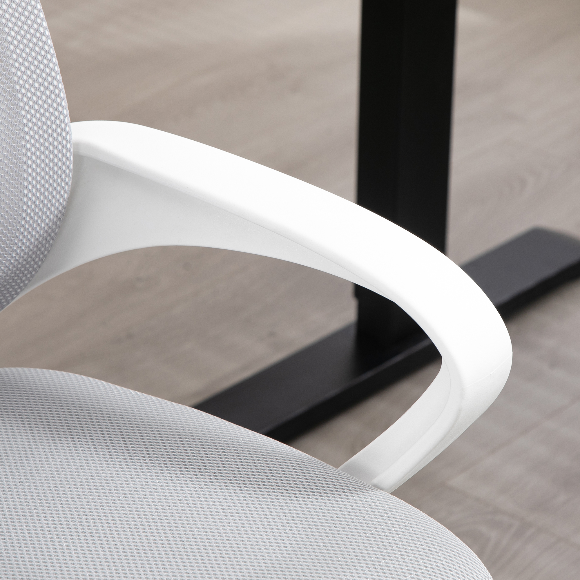 Primer plano del apoyabrazos blanco de una silla de oficina, conectado a un asiento gris, contra un suelo claro.