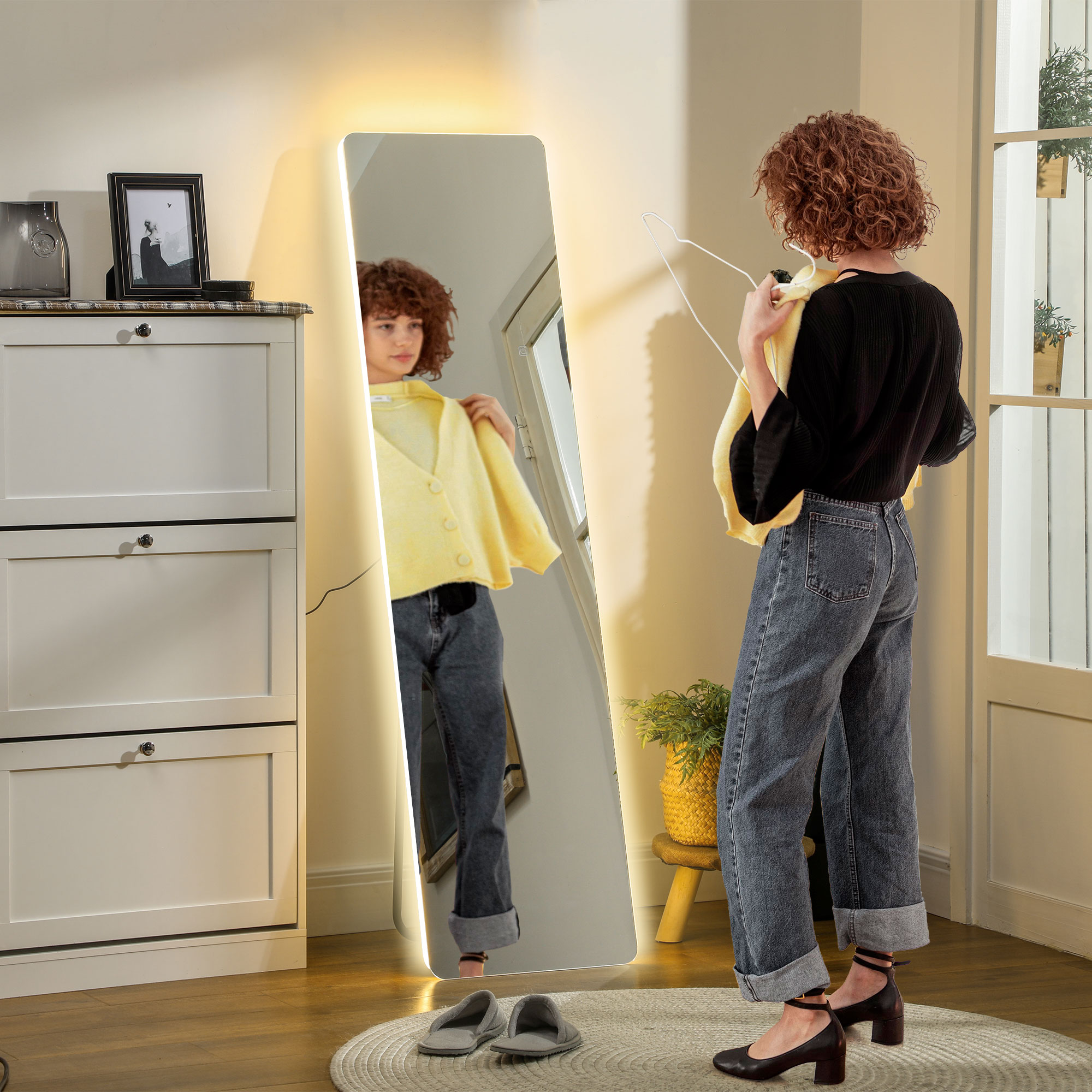Mujer en jeans mirándose en un espejo de cuerpo entero. El espejo tiene un marco brillante.