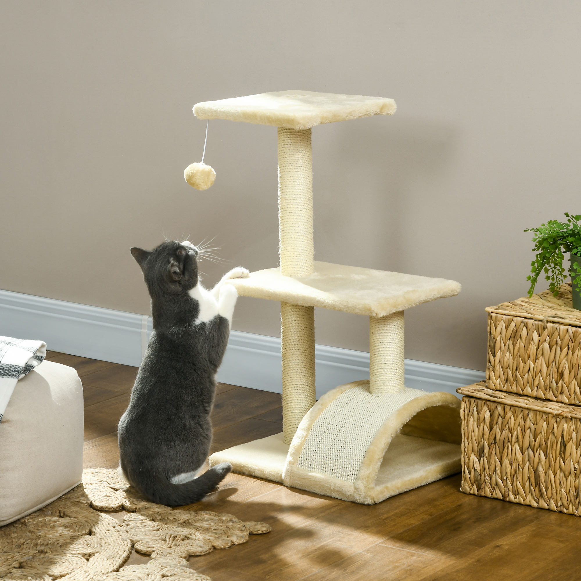 Un gato se para sobre sus patas traseras alcanzando un juguete colgante en un rascador.