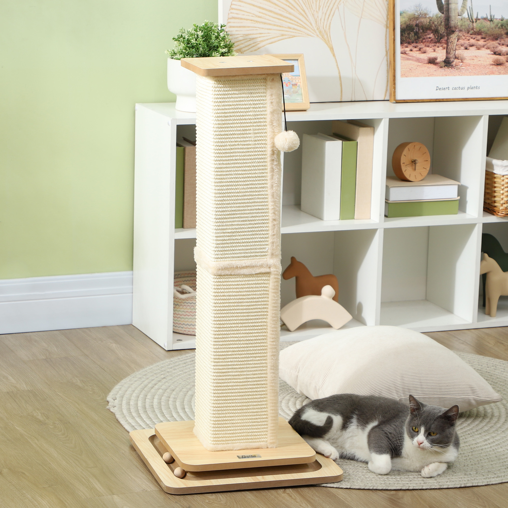 Un rascador para gatos y un gato tumbado en el suelo. El fondo tiene una estantería con decoración.