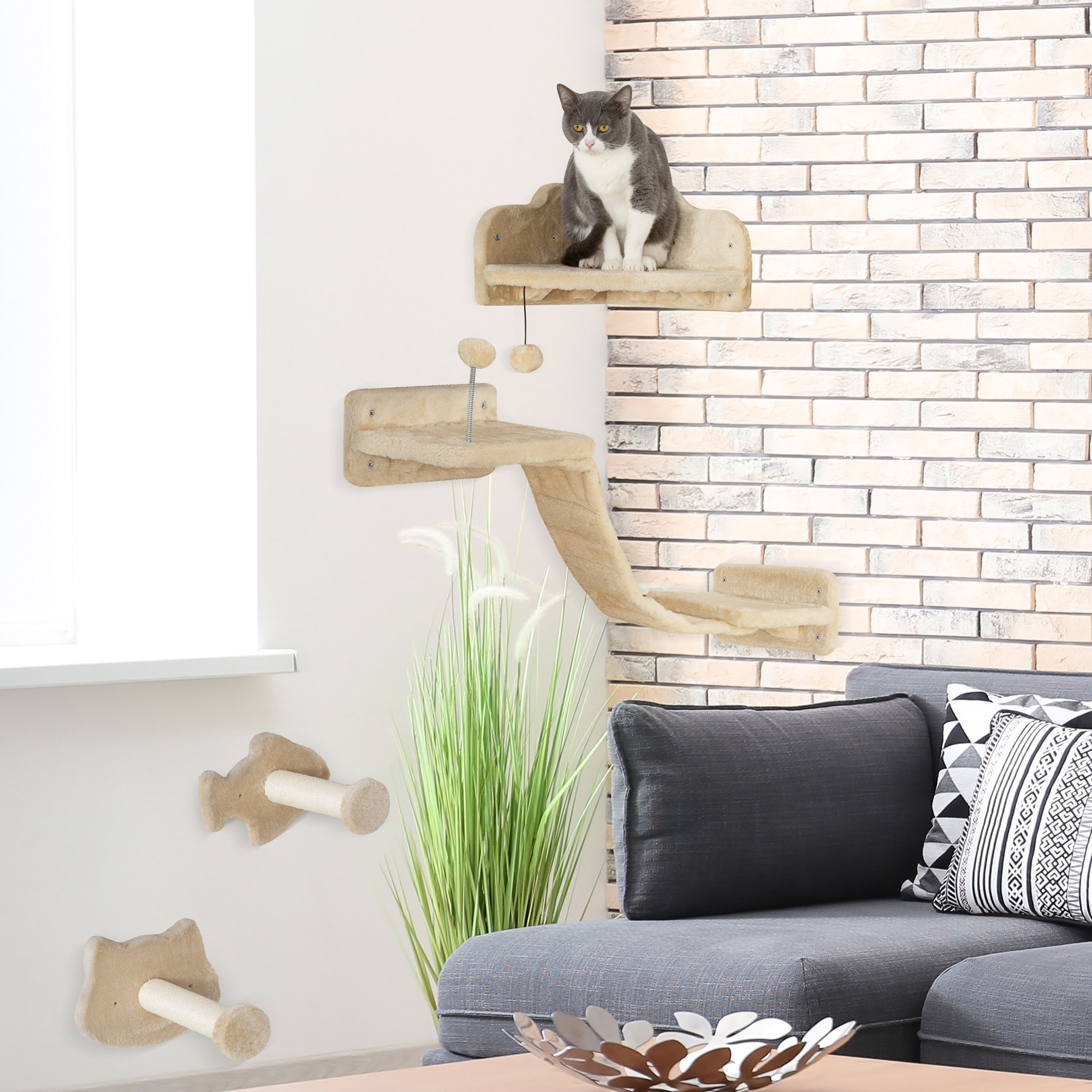 Un gato se sienta en una estantería beige para gatos en una pared de ladrillo, con otras estanterías y una planta.