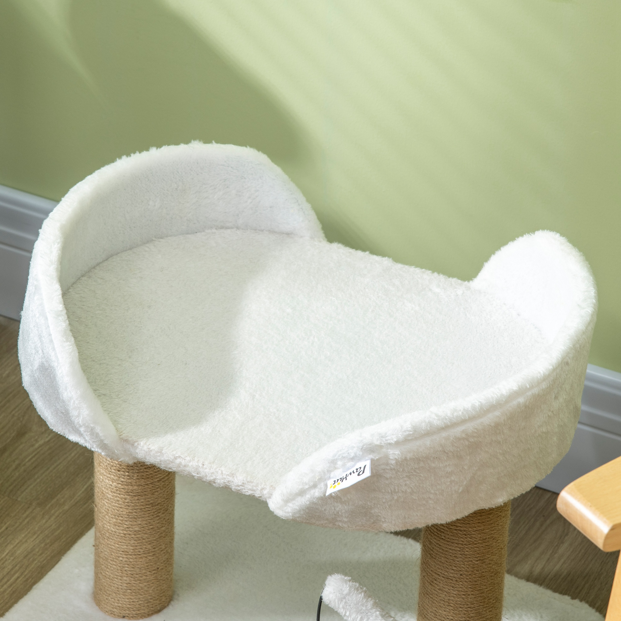 Cama para gatos blanca sobre un poste de madera, con textura blanca y esponjosa y etiqueta pequeña.