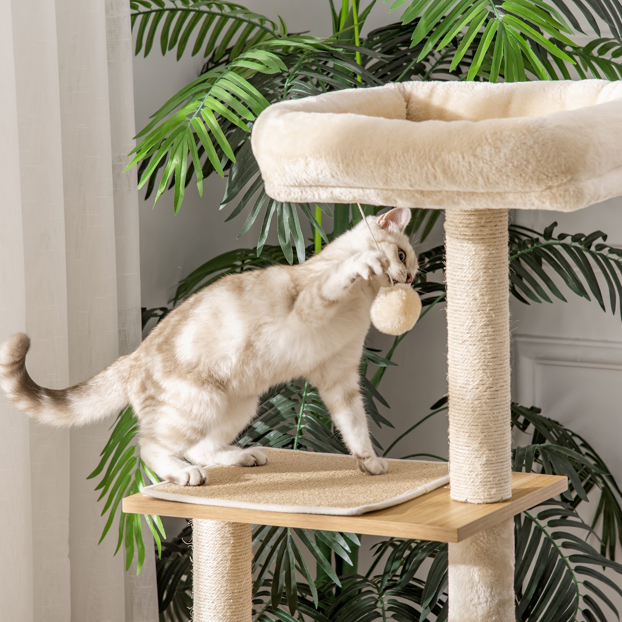 Un gato juega con un juguete en un árbol para gatos. El gato es marrón claro y blanco.
