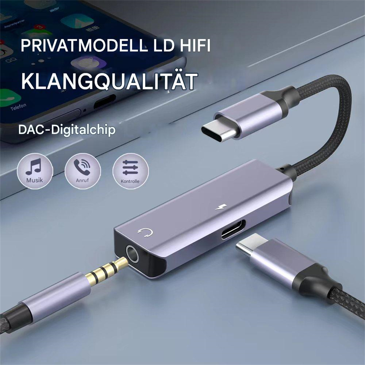 Grauer Adapter mit zwei USB-C-Anschlüssen und 3,5-mm-Klinke. Schwarz-weißer Hintergrund.