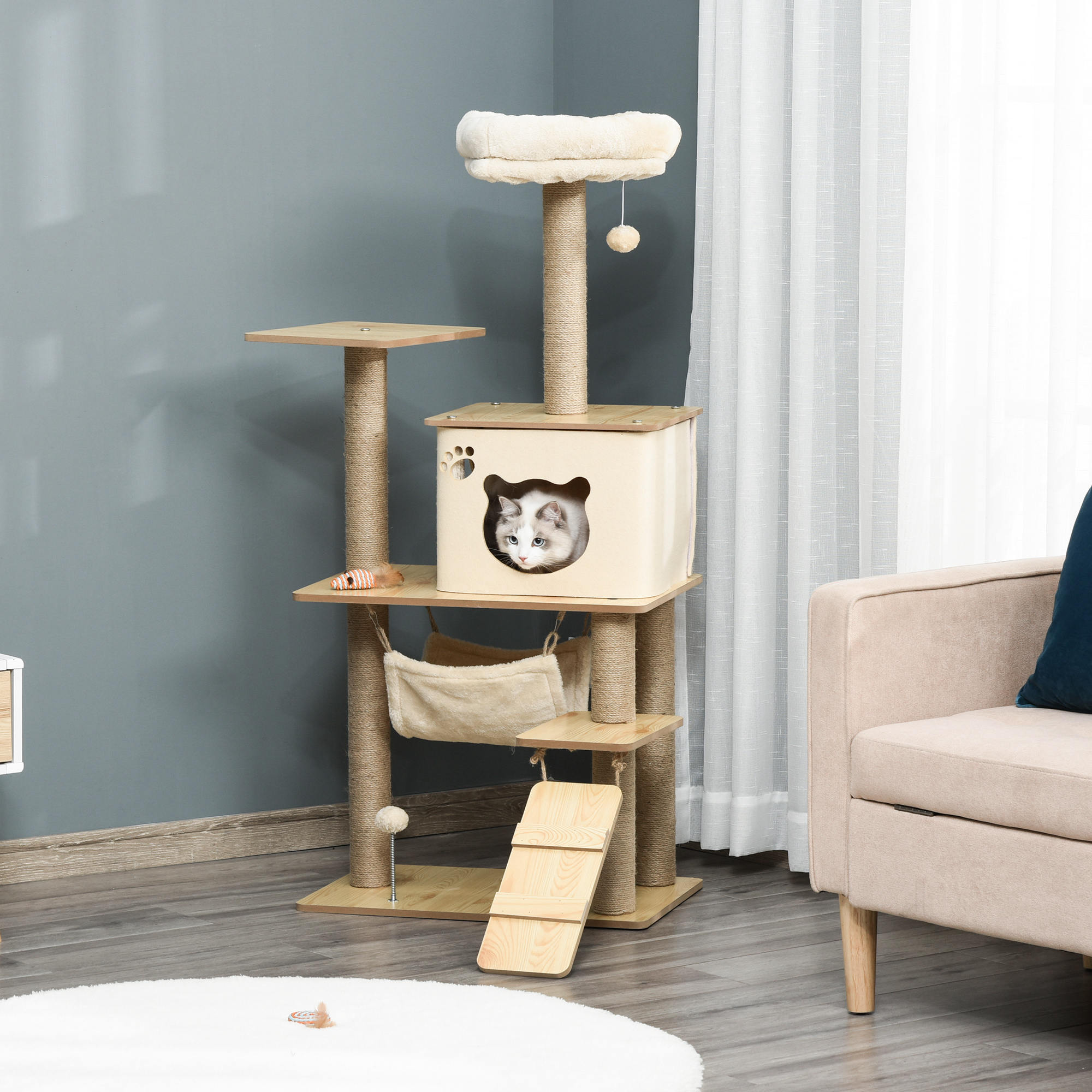 Un gato asomándose por una casa de árbol para gatos beige con un juguete colgante.