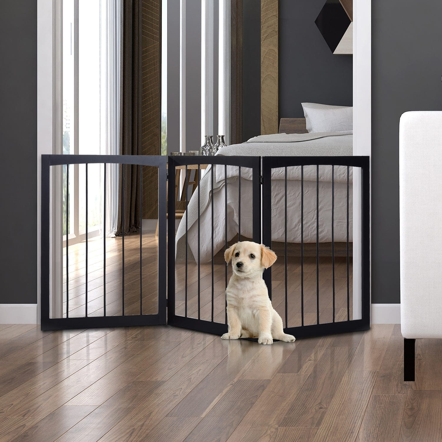 Un cachorro sentado dentro de una puerta para perros negra y de madera en interiores.