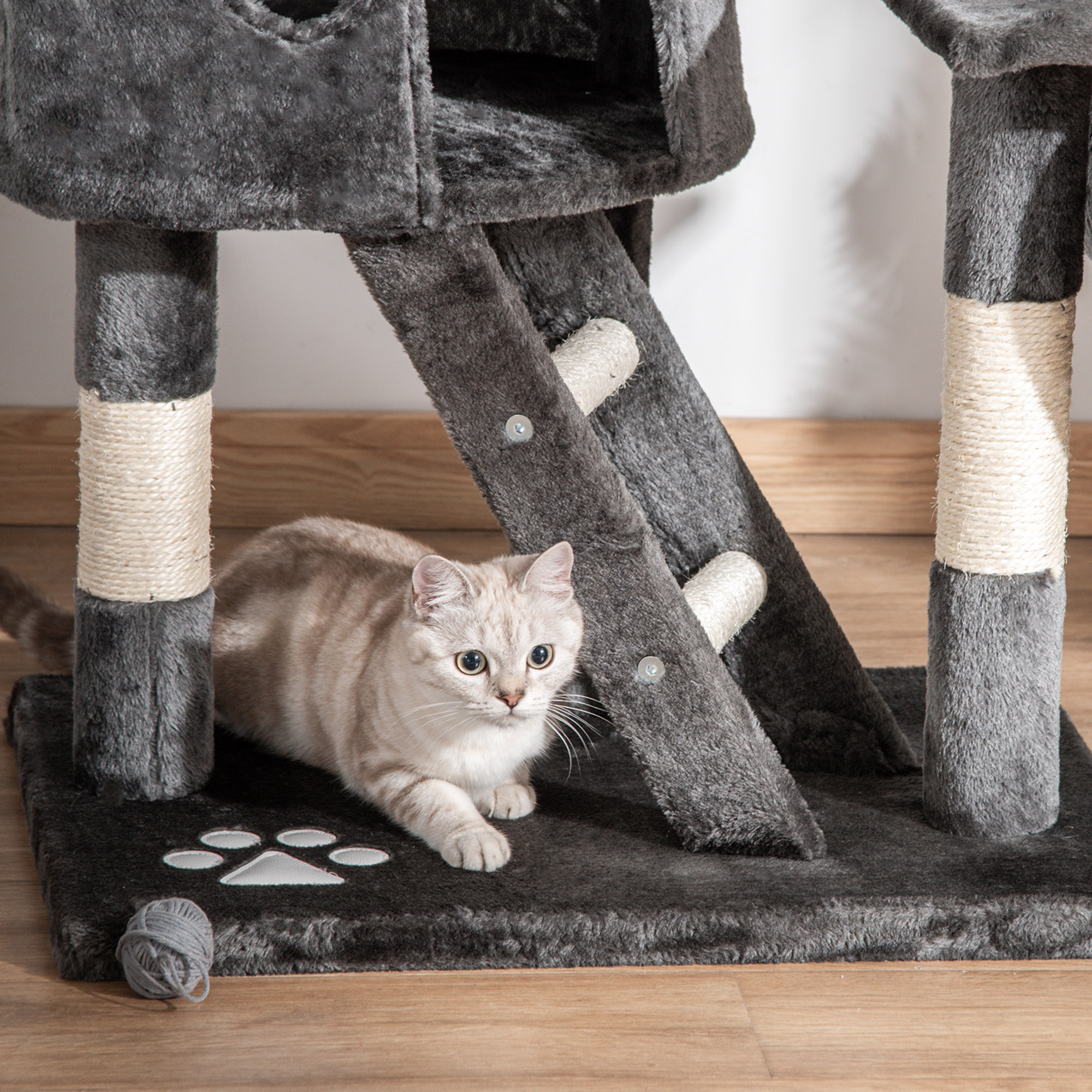 Árbol para gatos con un gato. El gato es de color claro, sentado en la base.