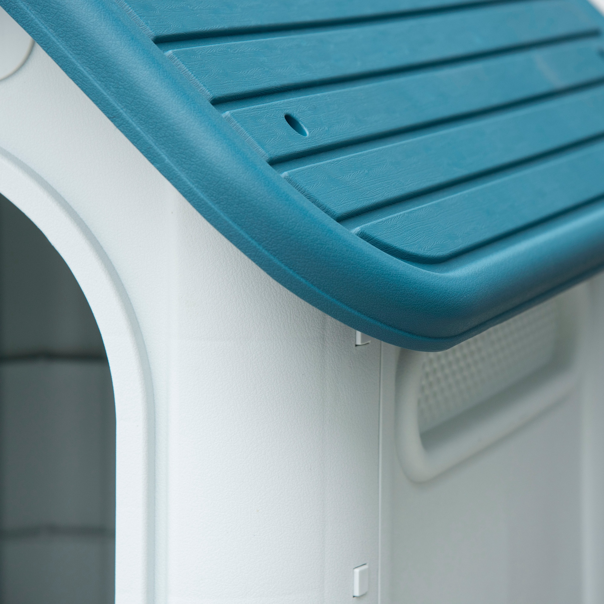 Primer plano de una caseta para perros. Es blanca con techo azul. El diseño es sencillo.
