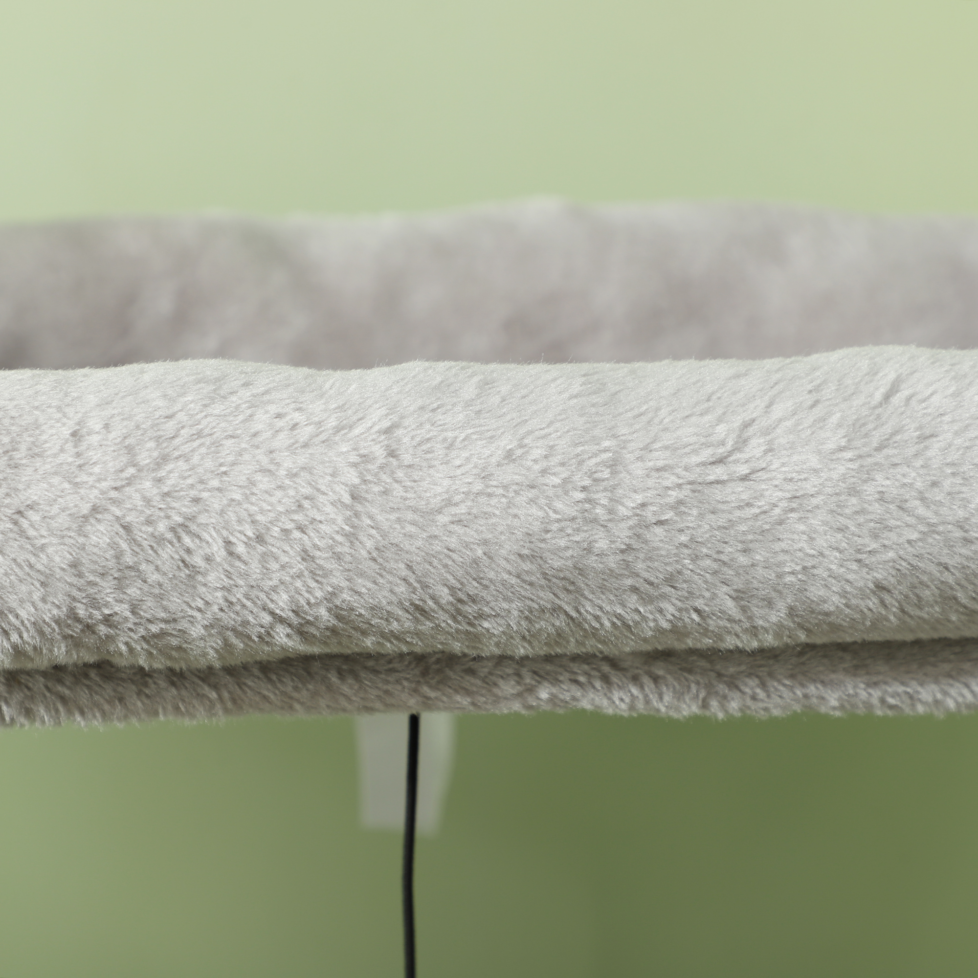 Primo piano di una superficie grigia e soffice di un albero per gatti, con sfondo verde.