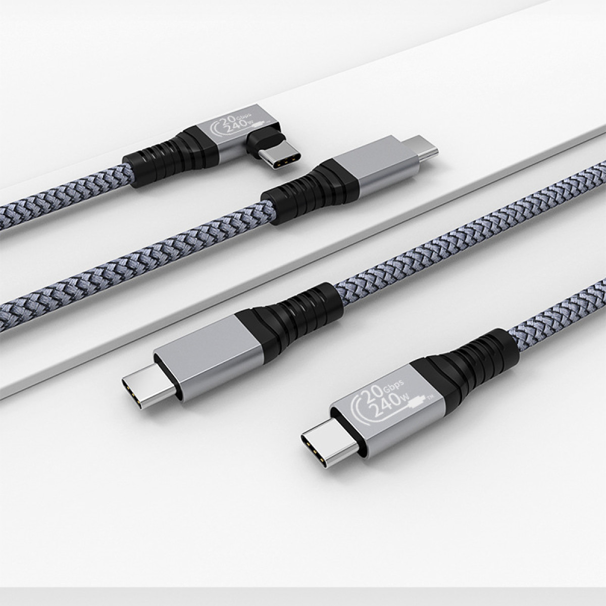 Vier USB-C-Kabel mit grauen geflochtenen Hüllen und silbernen Steckern, auf einer weißen Oberfläche.
