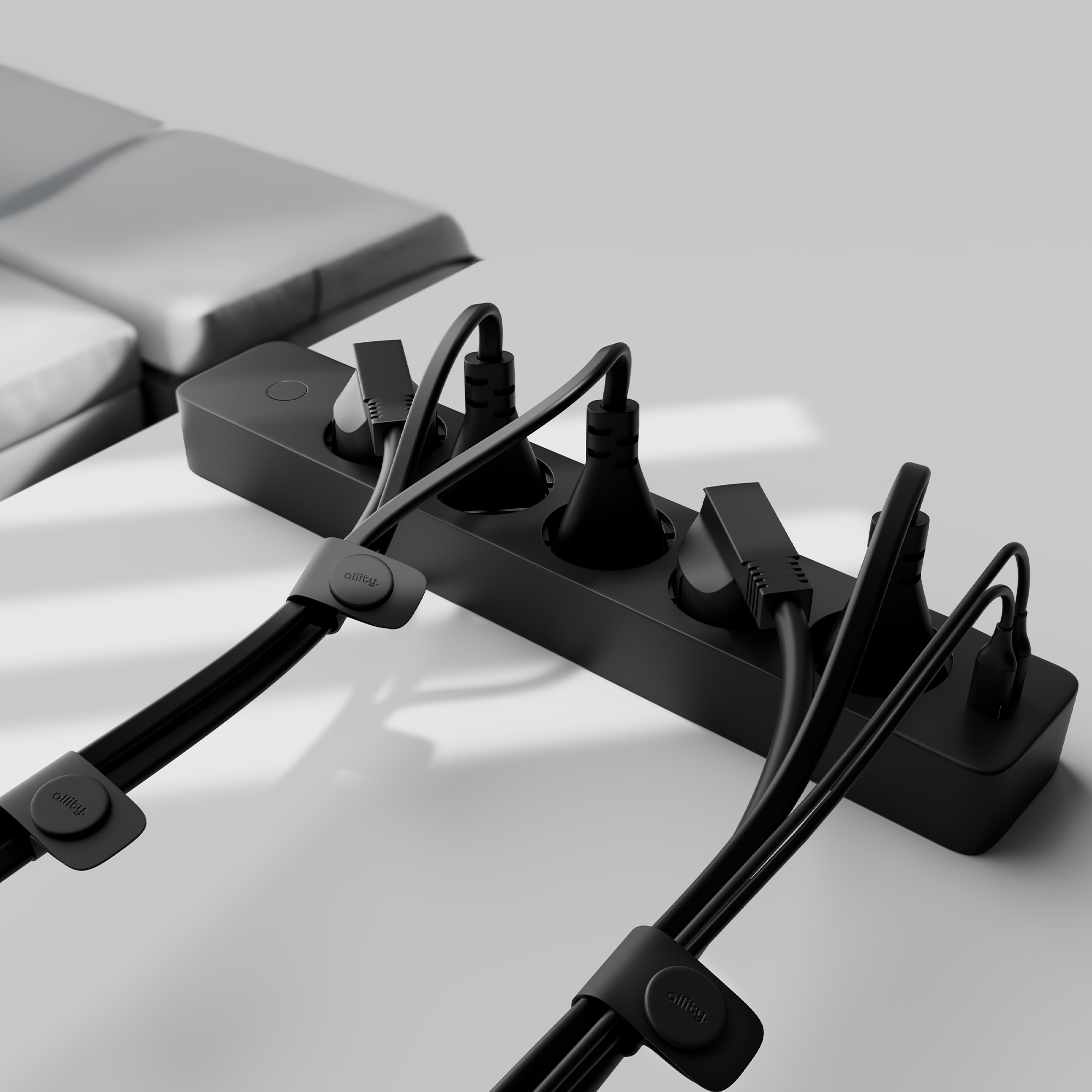 Czarna listwa zasilająca z wieloma podłączonymi wtyczkami na białej powierzchni.