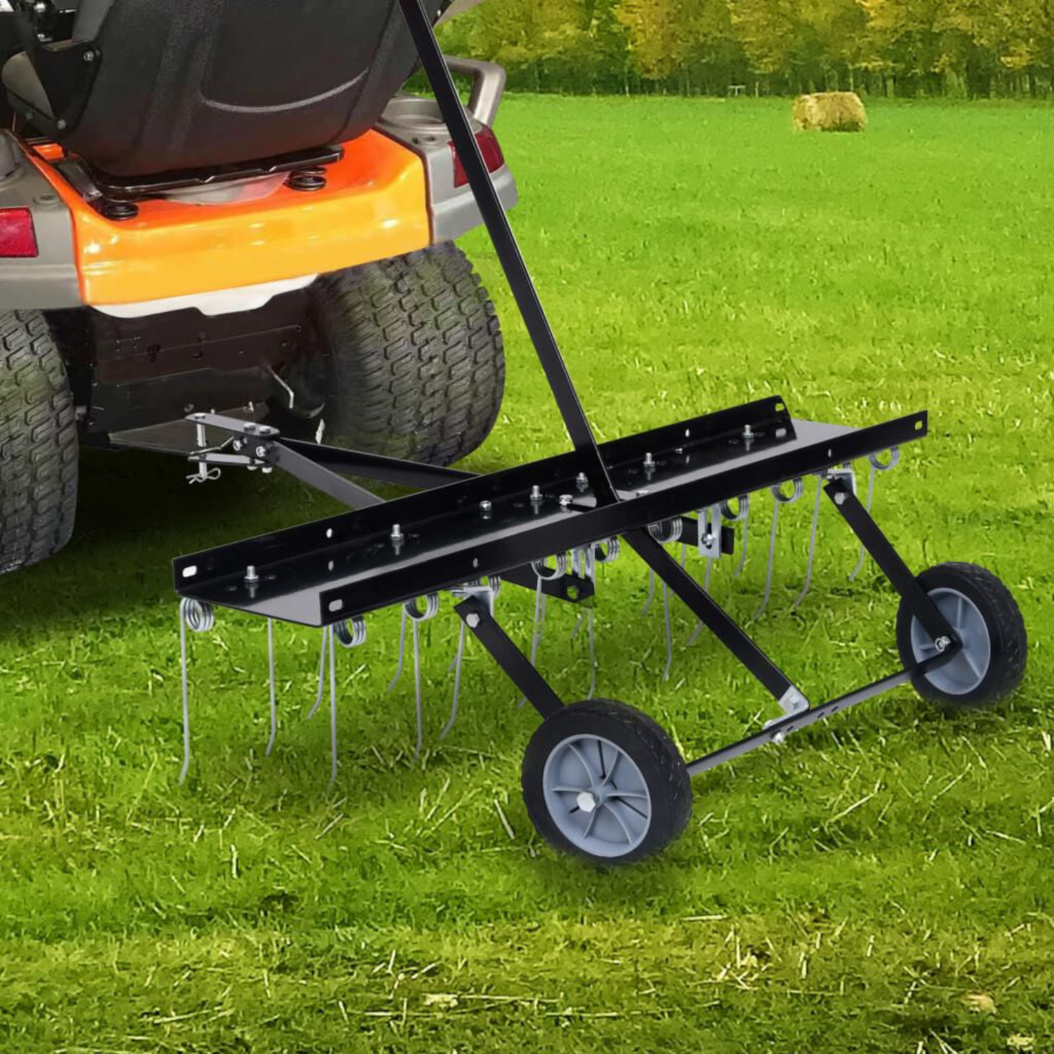 Ein Rasenlüfter, der an einem Traktor befestigt ist, steht auf grünem Gras. Der Hintergrund zeigt Bäume und Heu.