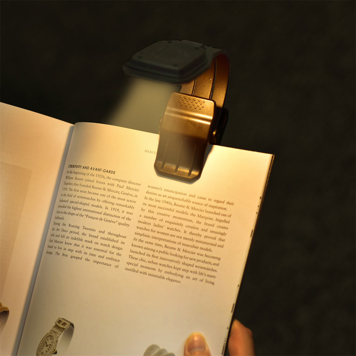 Buch mit einer Leseleuchte zum Anklemmen. Licht beleuchtet die Seite. Weißer Hintergrund.