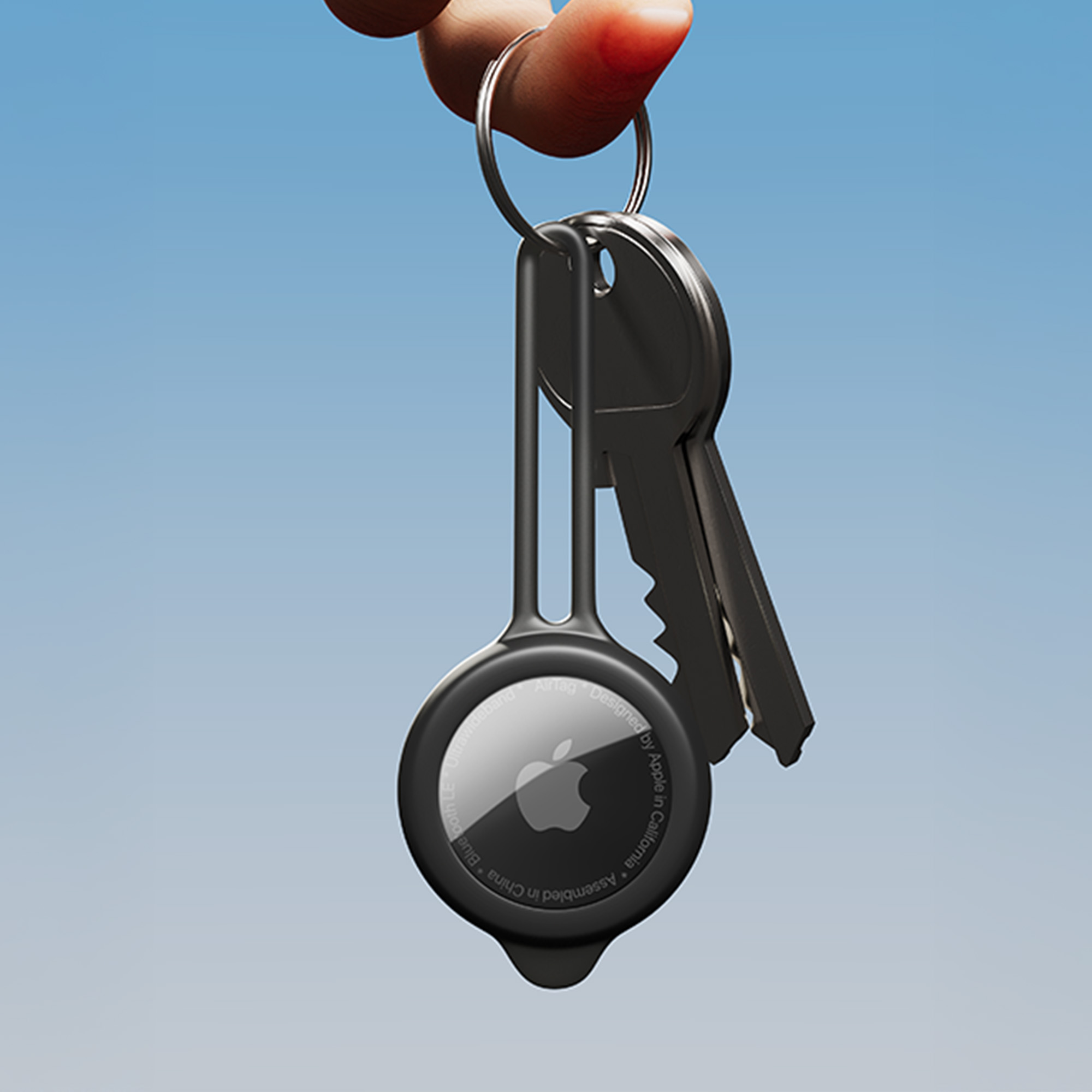 Apple AirTag z kluczami na breloczku. Trzymany na tle błękitnego nieba.