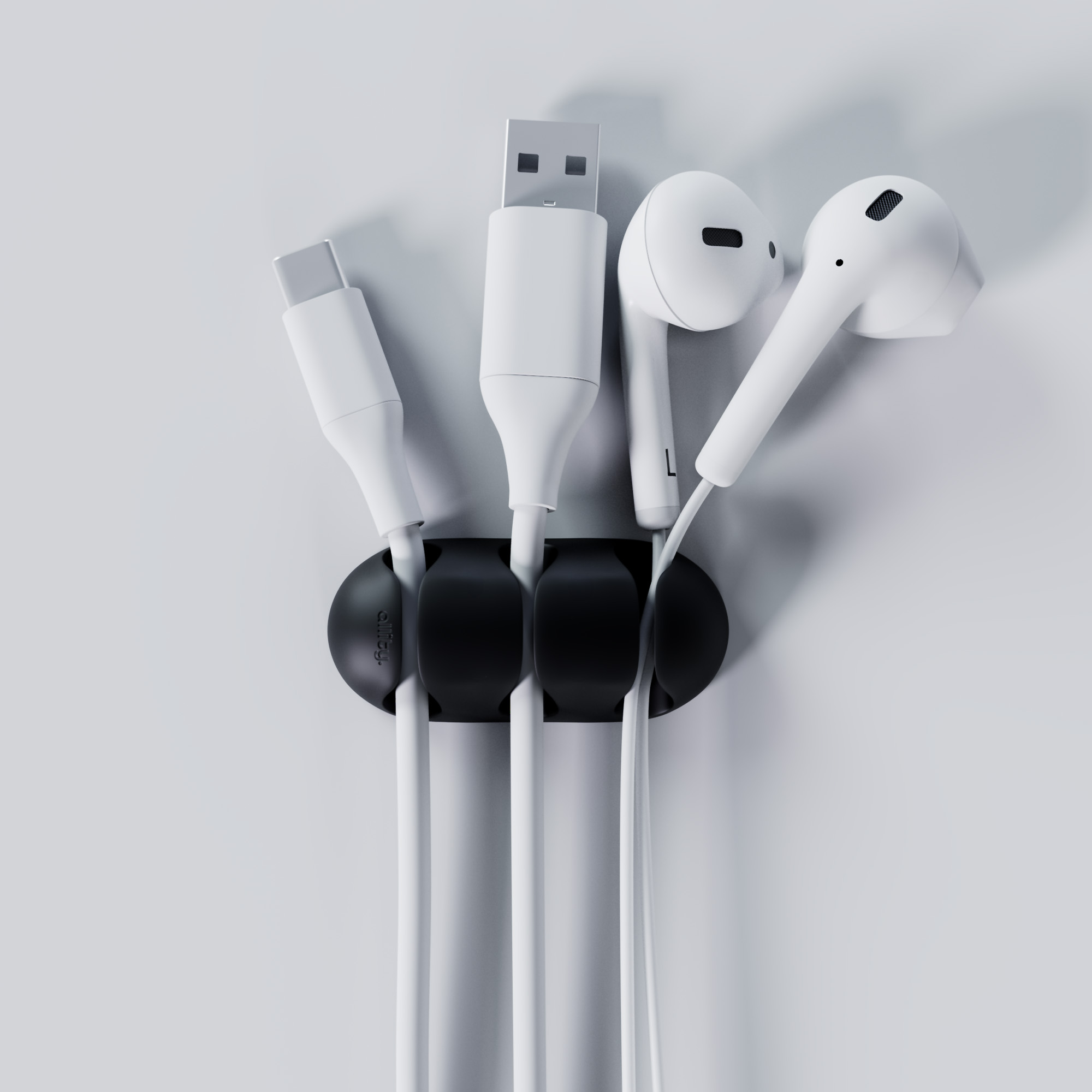 Czarny organizer kabli trzymający białe kable USB-C, USB i słuchawek.