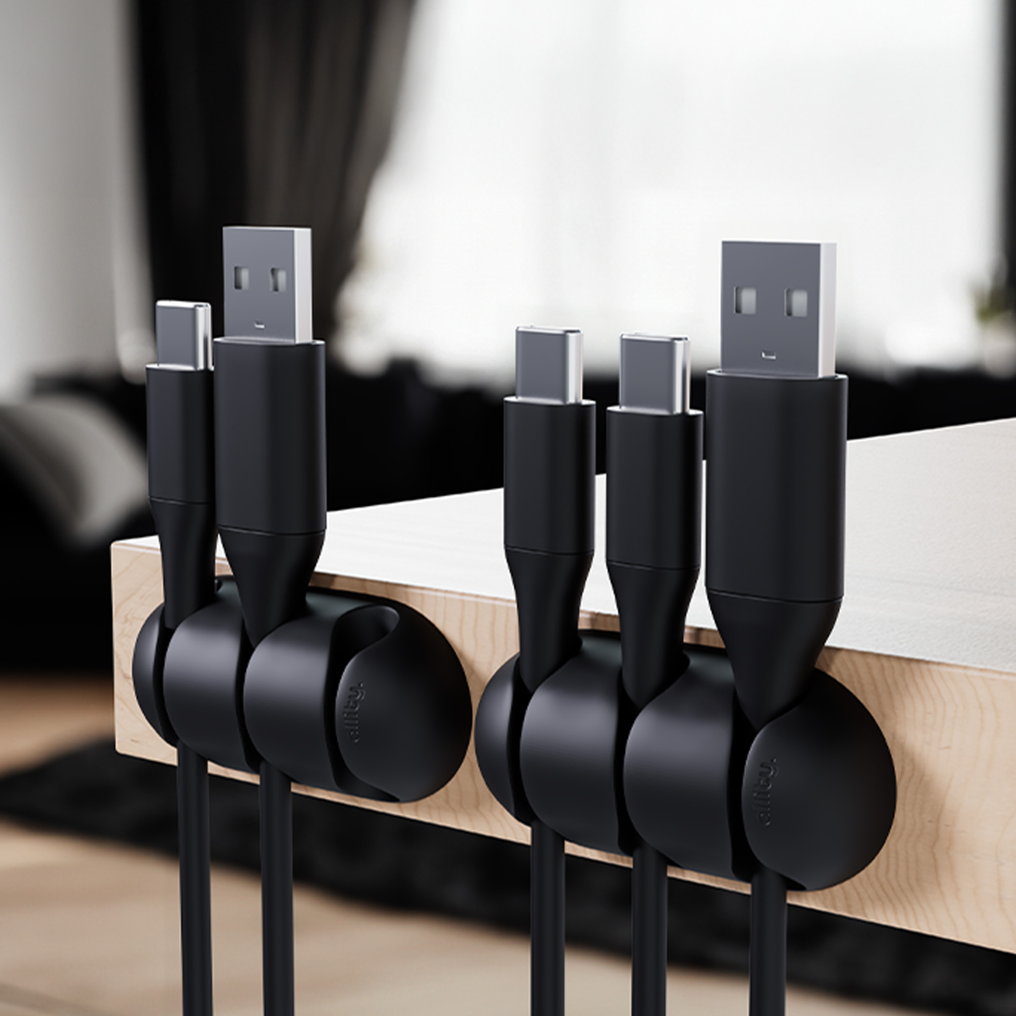 Cztery czarne organizery kabli trzymające kable USB i USB-C.